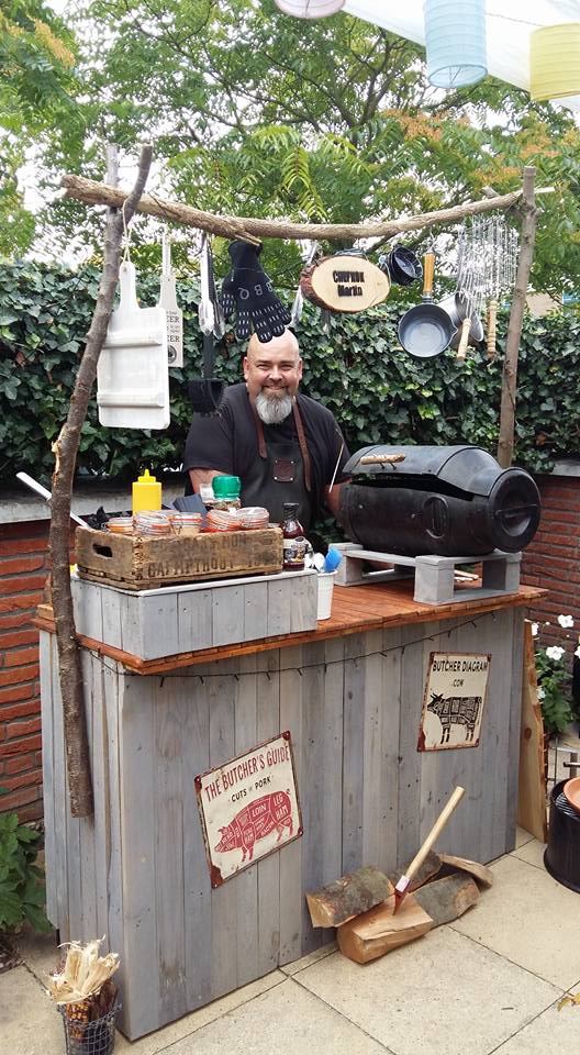 Chefkok Martin bij zijn rustieke barbecuekraam met een barbecue gemaakt van een oude melkbus.