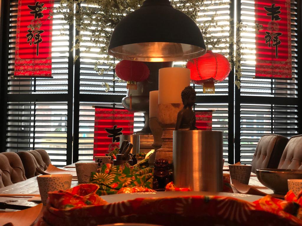 Een rijkversierde eettafel met kaarsen, lantaarns en Chinese decoraties voor een raam.