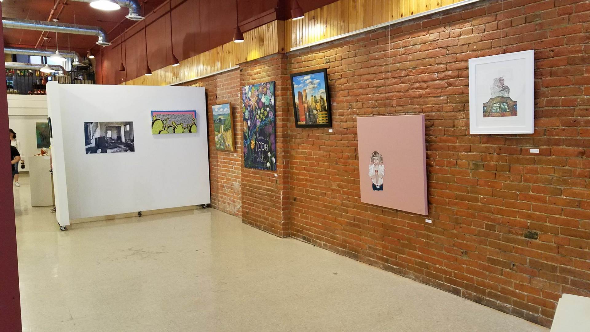 A room with a brick wall and paintings on the wall.