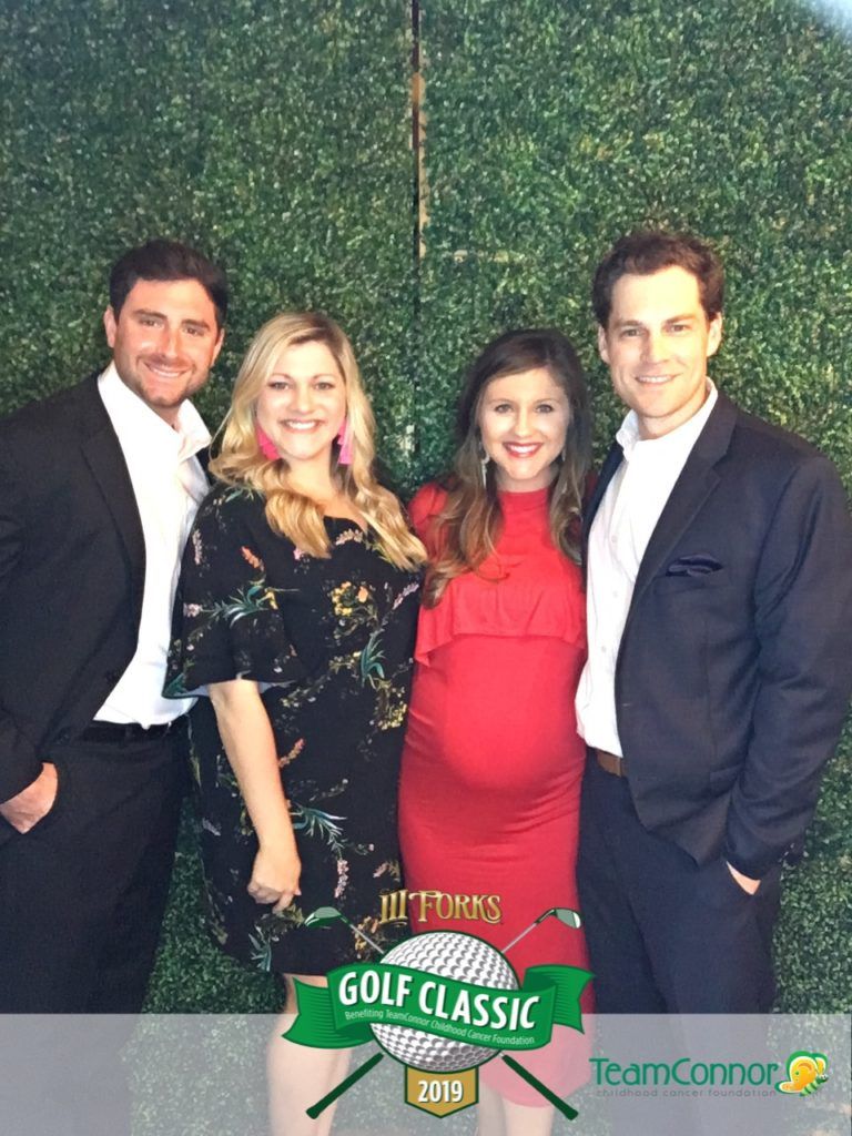 A group of people standing next to each other in front of a green wall.