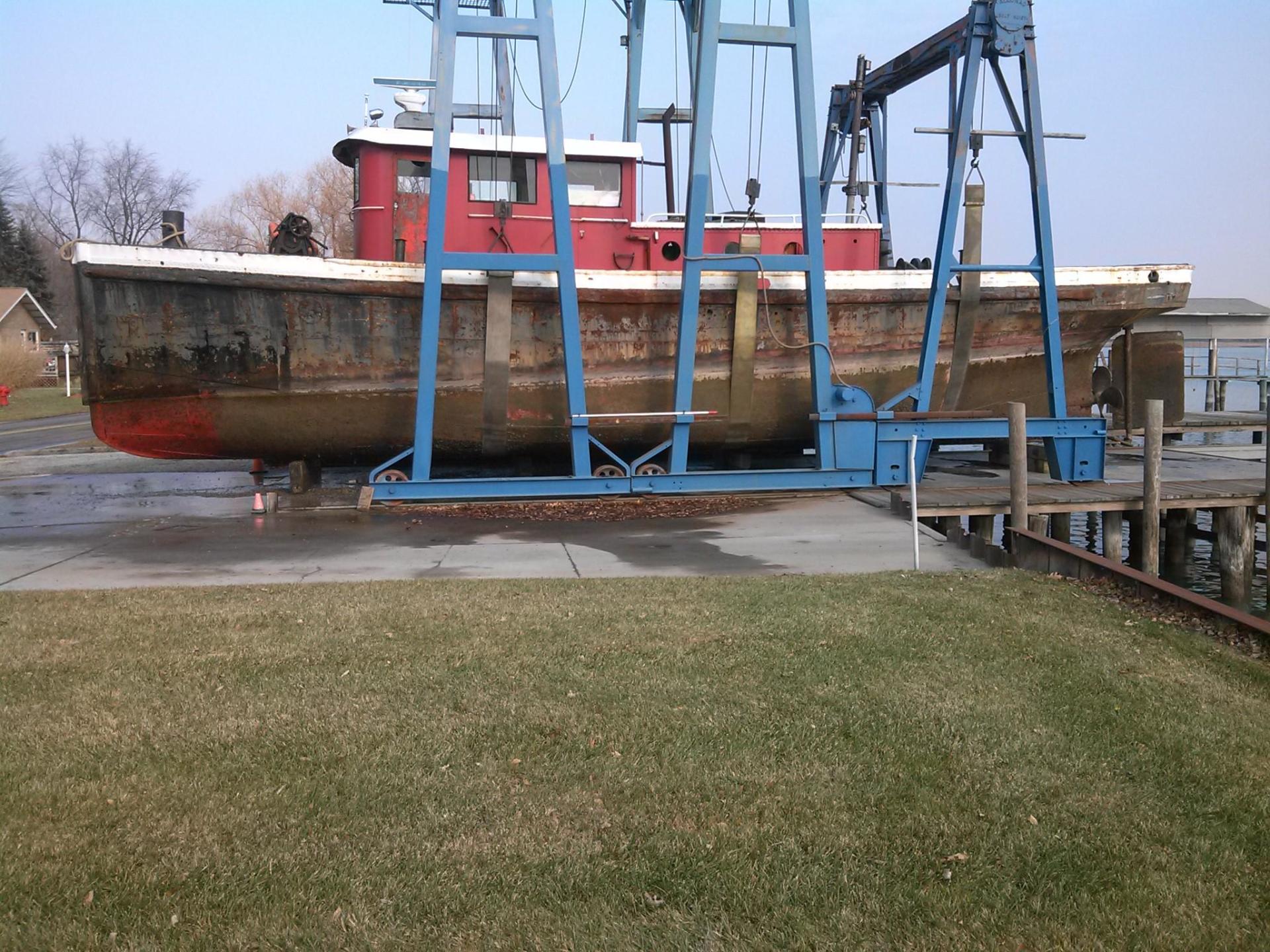 A red and white boat is being lifted by a crane