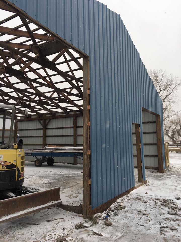 A yellow forklift is parked in front of a blue building