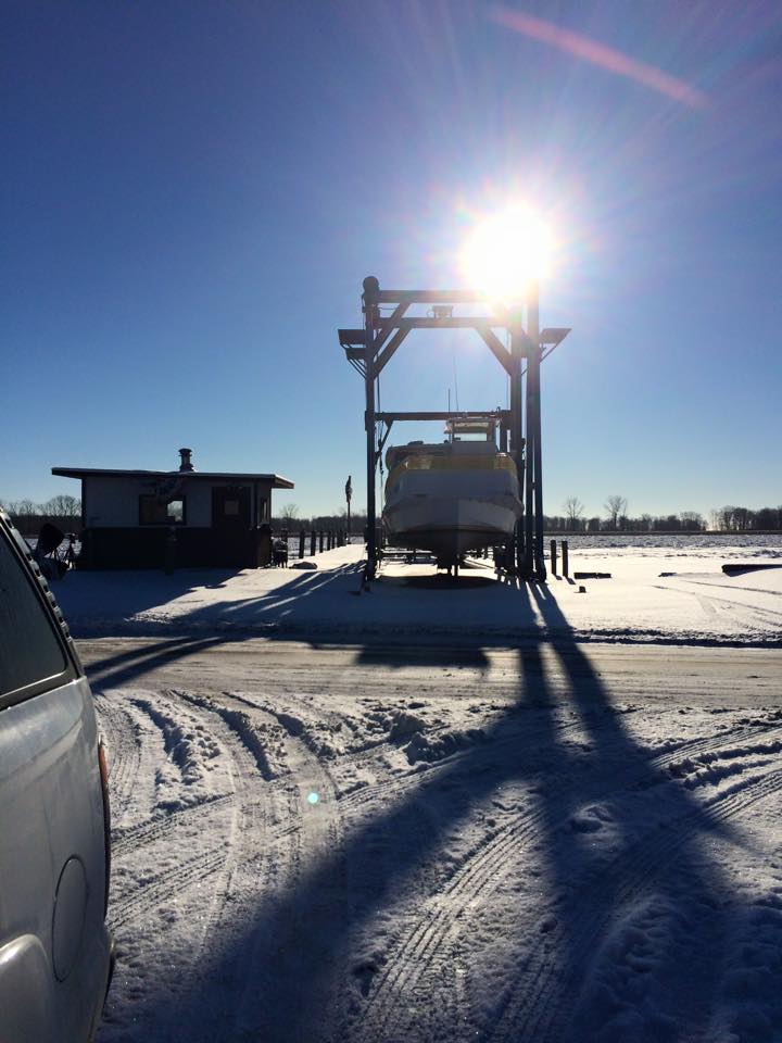 A boat is being lifted by a crane in the snow