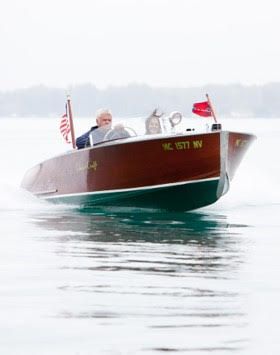 A man is driving a boat with an American flag in the back