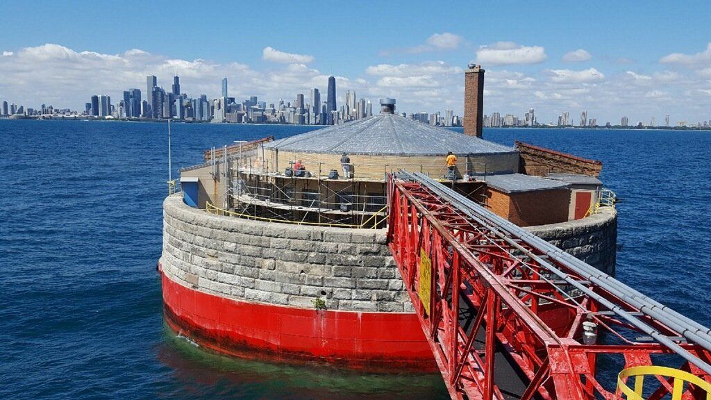 A red bridge over a body of water with a city skyline in the background