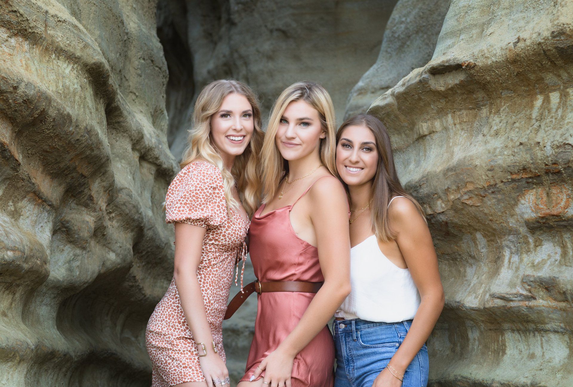 Three women are posing for a picture in front of a rock formation.