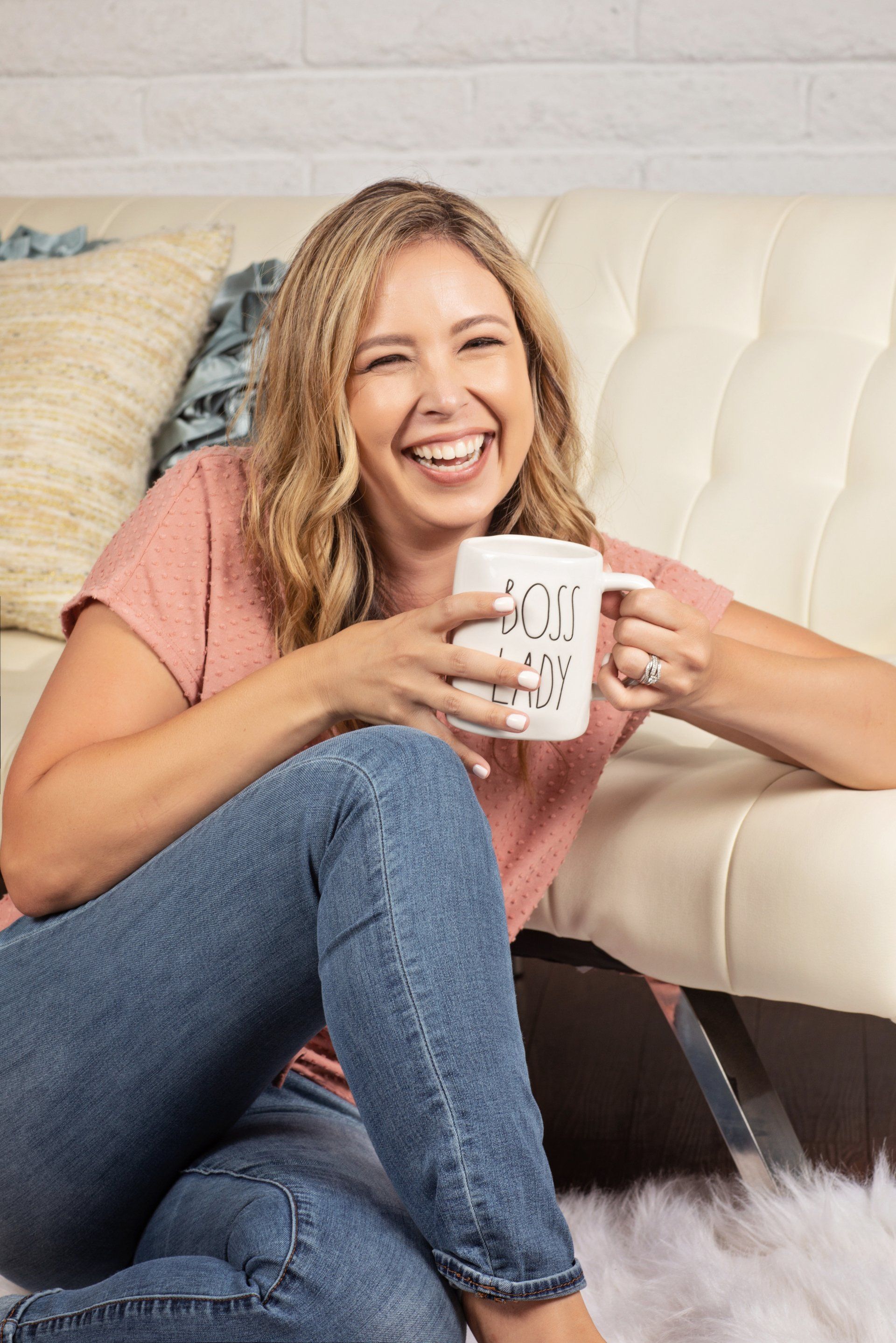 A woman is sitting on the floor holding a cup of coffee.
