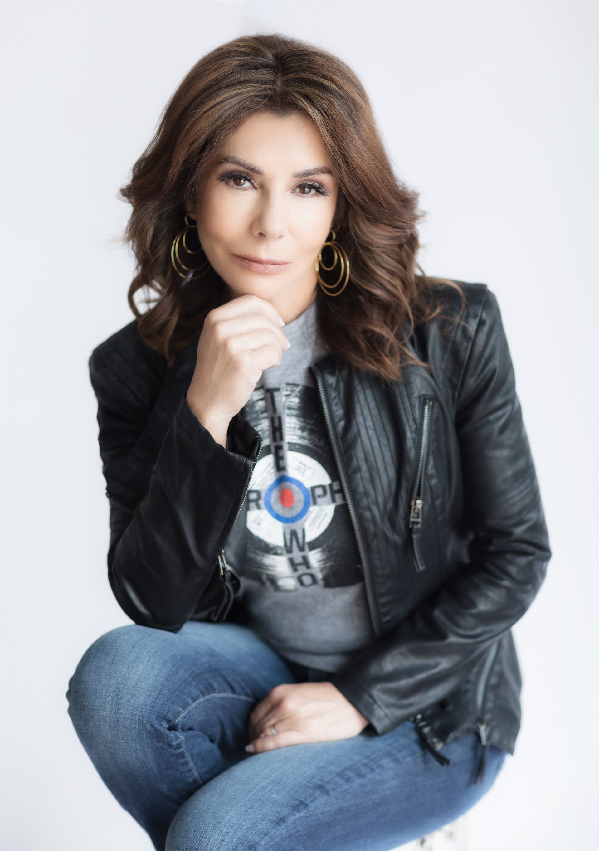 A woman wearing a black leather jacket is sitting on a chair
