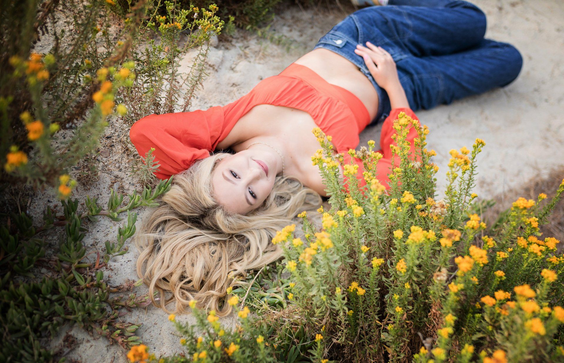 A woman is laying on the ground in a field of flowers.