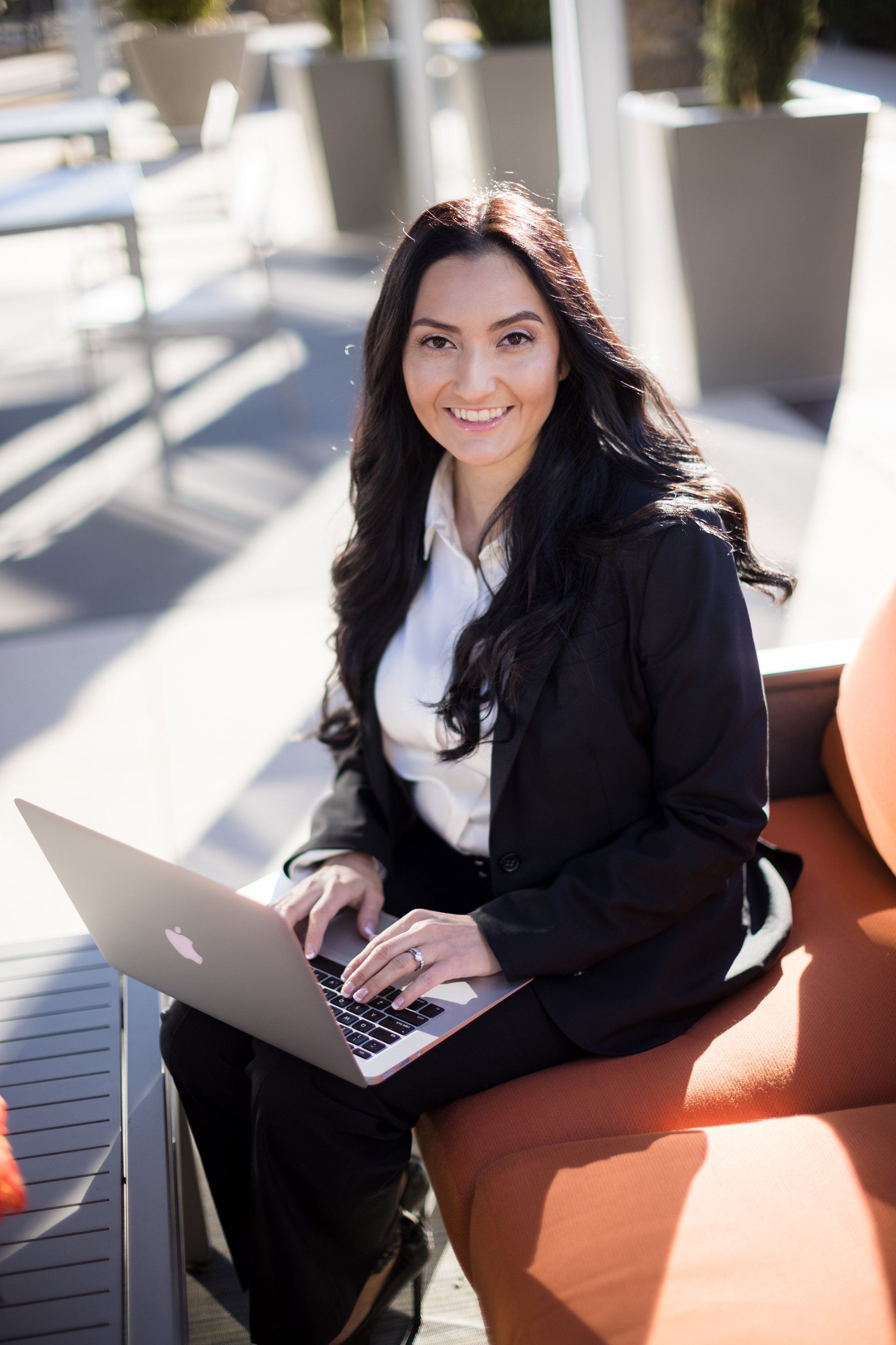 A woman is sitting on a couch using a laptop computer.