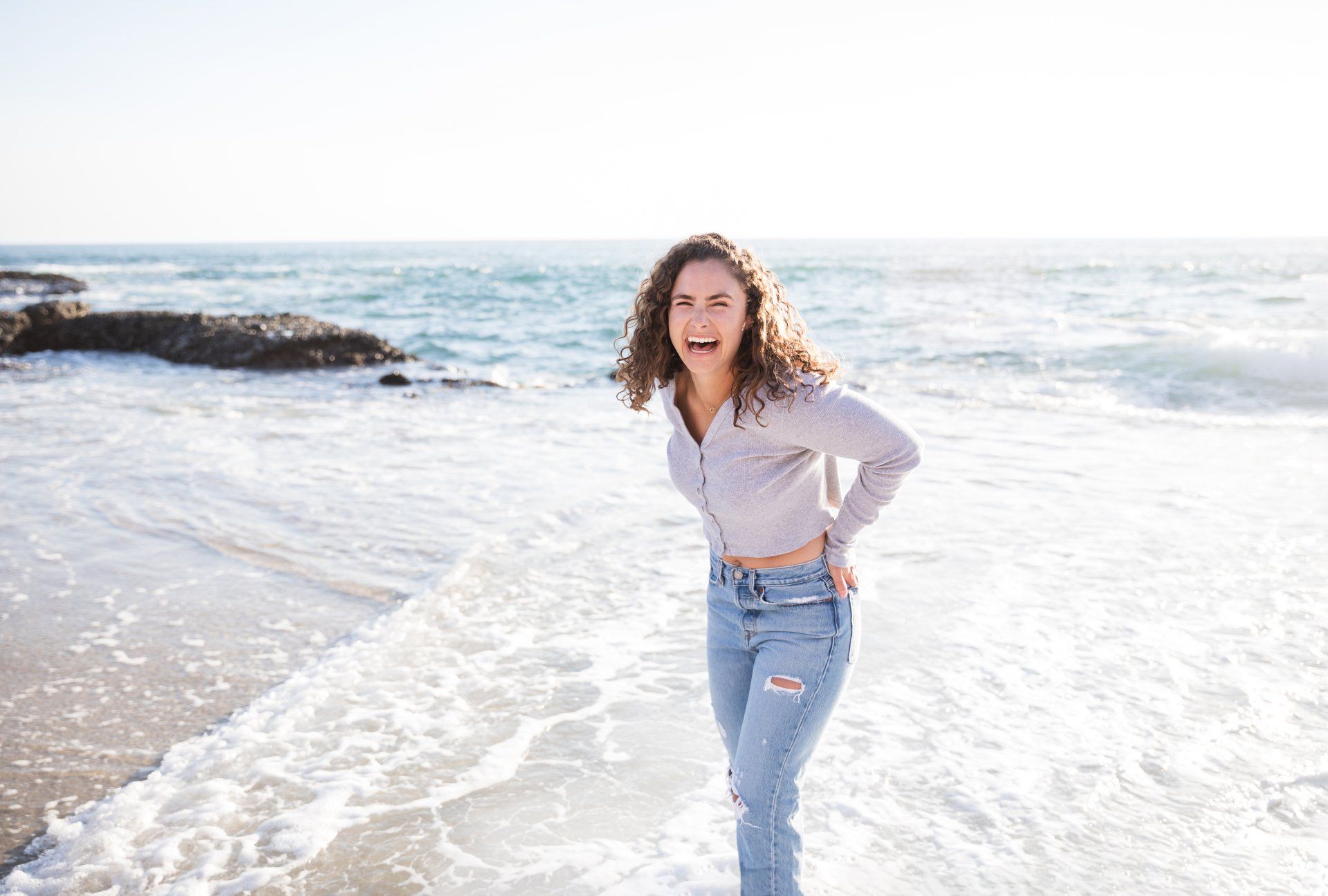 A woman is standing in the water on the beach.