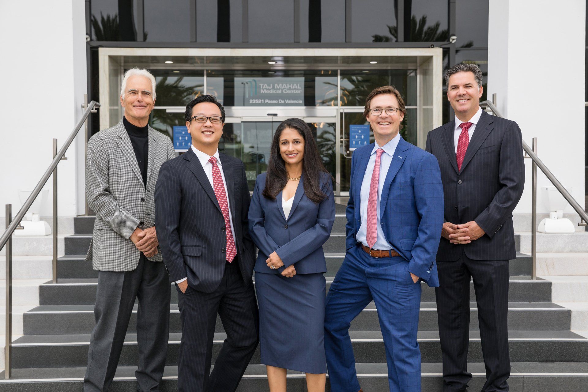 A group of people in suits and ties are posing for a picture in front of a building.