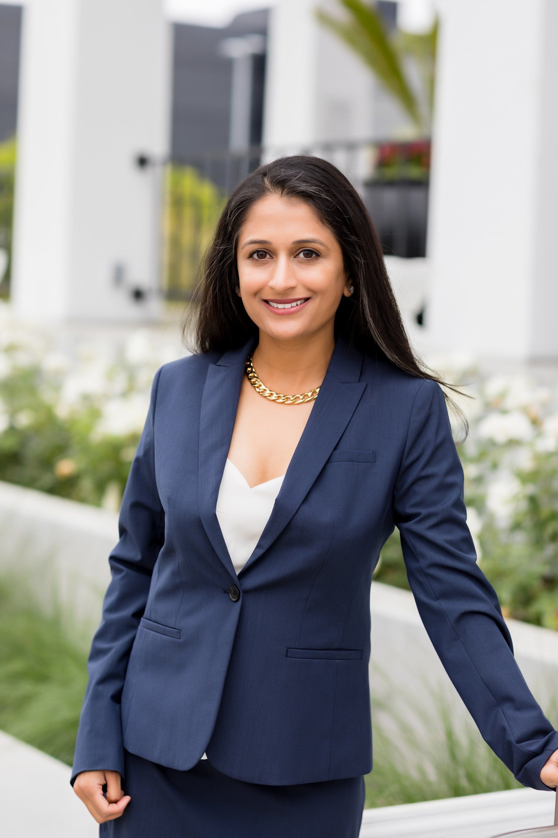 A woman in a blue suit is standing in front of a white building.