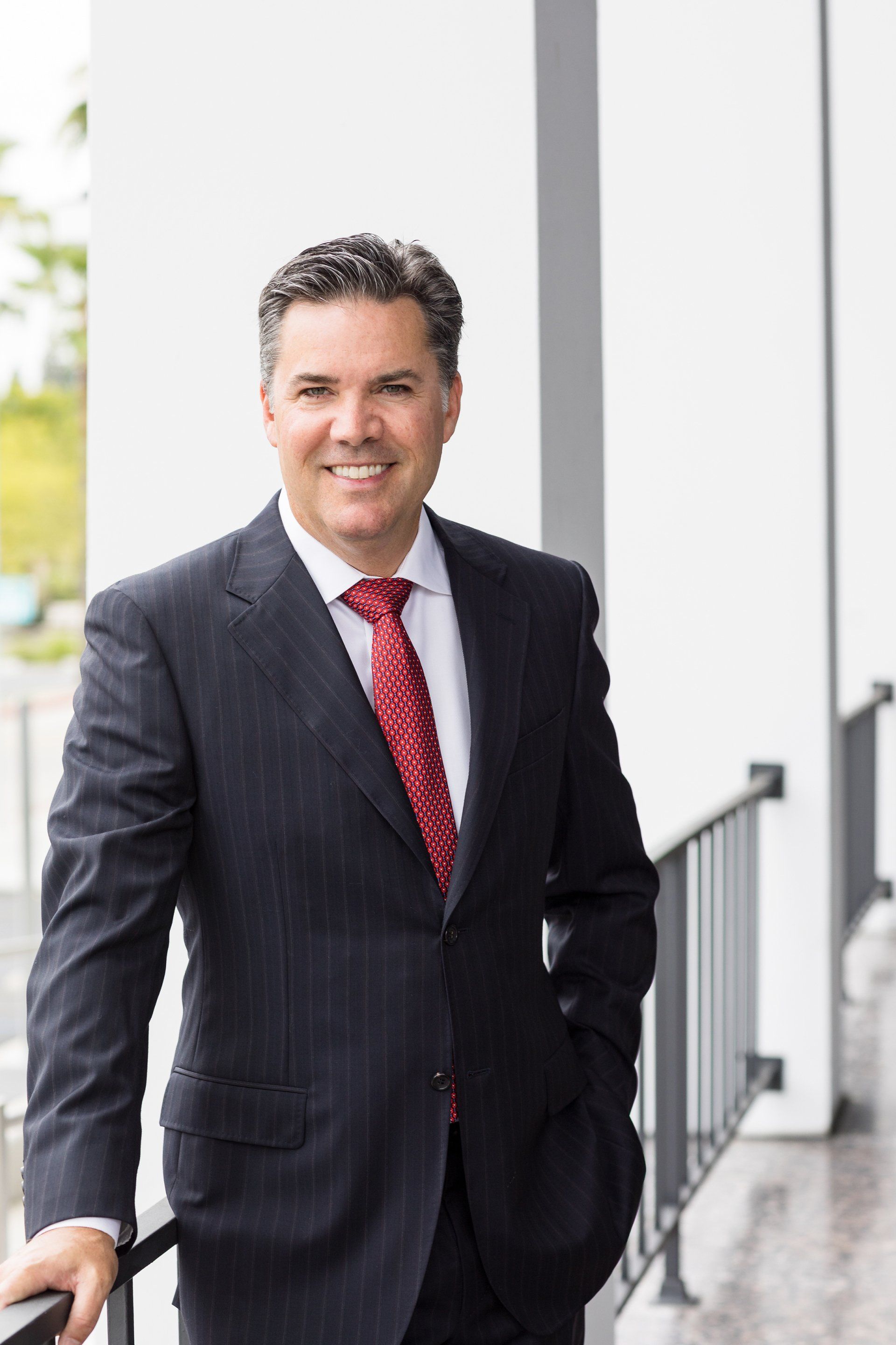 A man in a suit and tie is leaning on a railing.