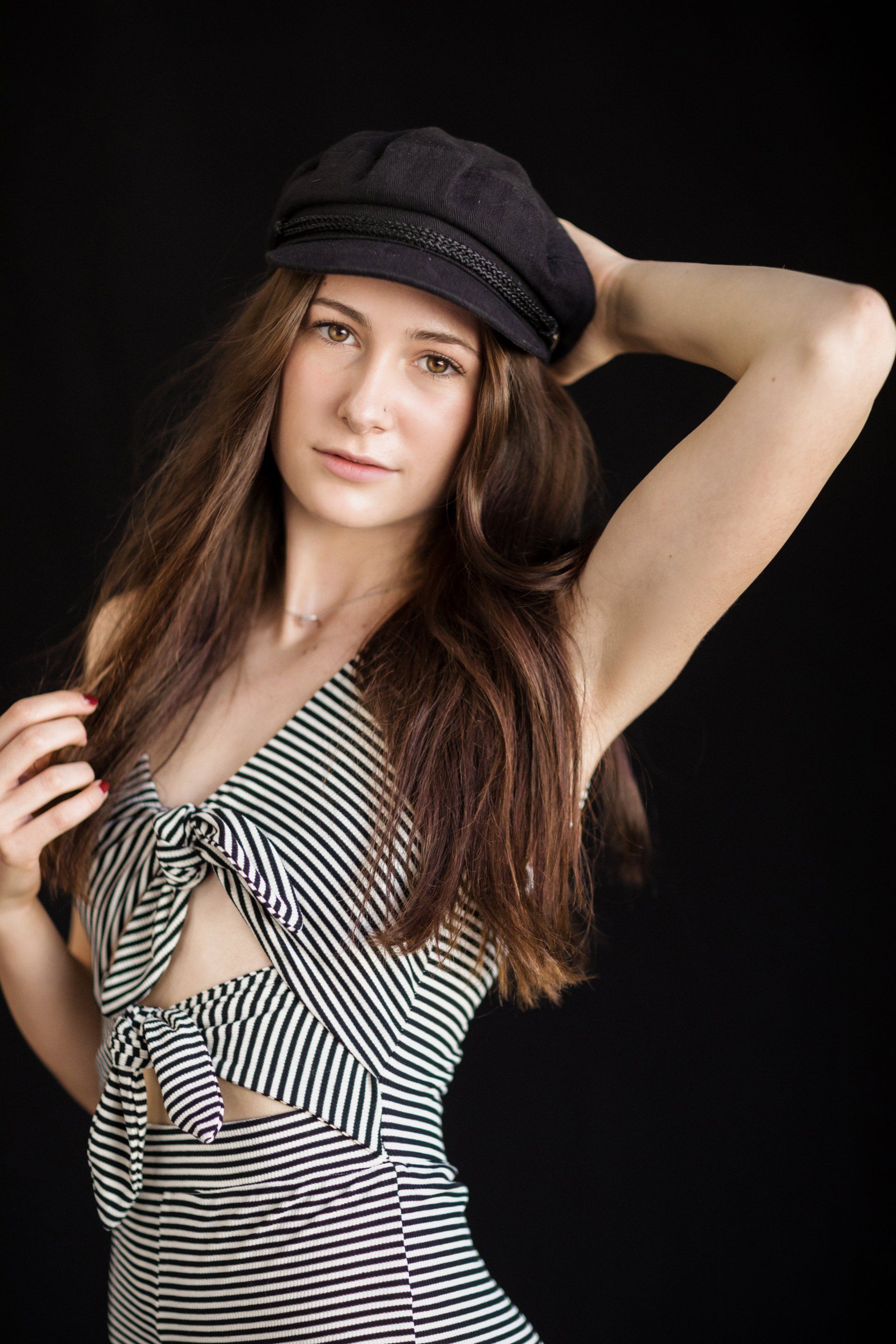 The woman is wearing a black hat and a striped dress.