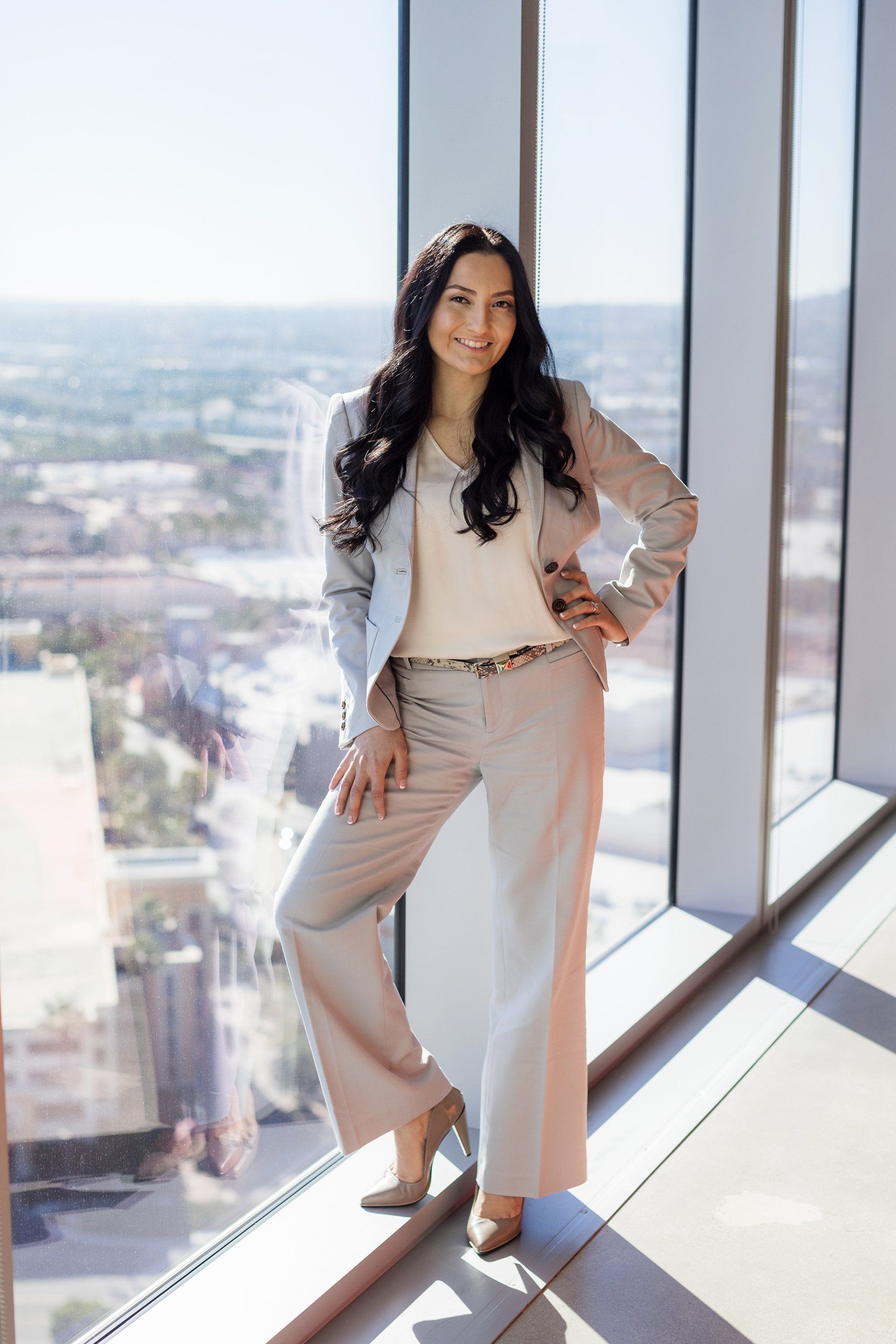 A woman in a suit is standing in front of a large window.