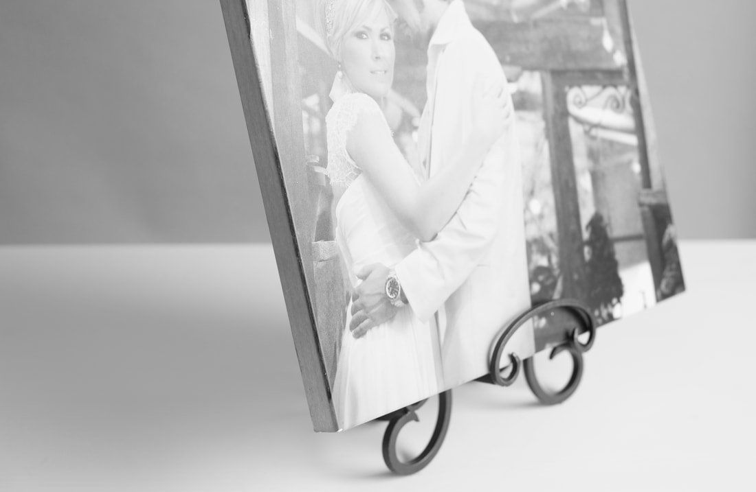 A black and white photo of a bride and groom on a metal stand.
