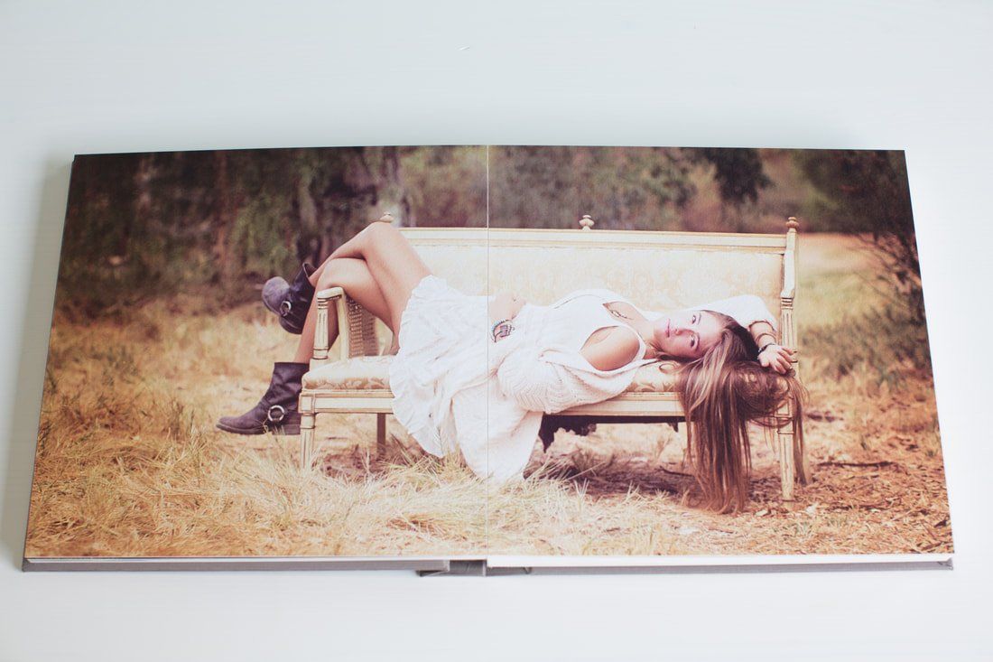 A woman in a white dress is laying on a wooden bench.