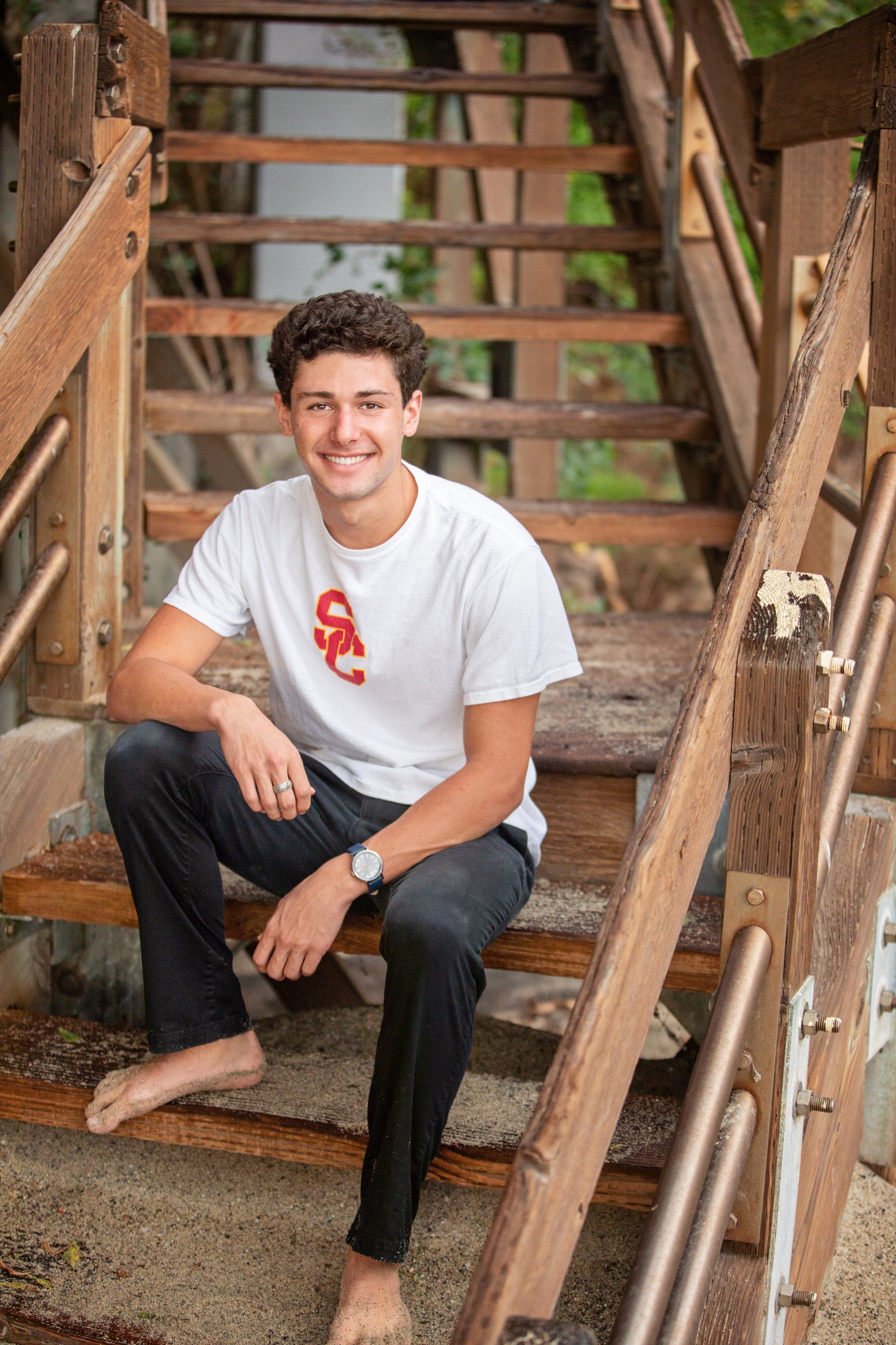 A young man is sitting on a set of wooden stairs.