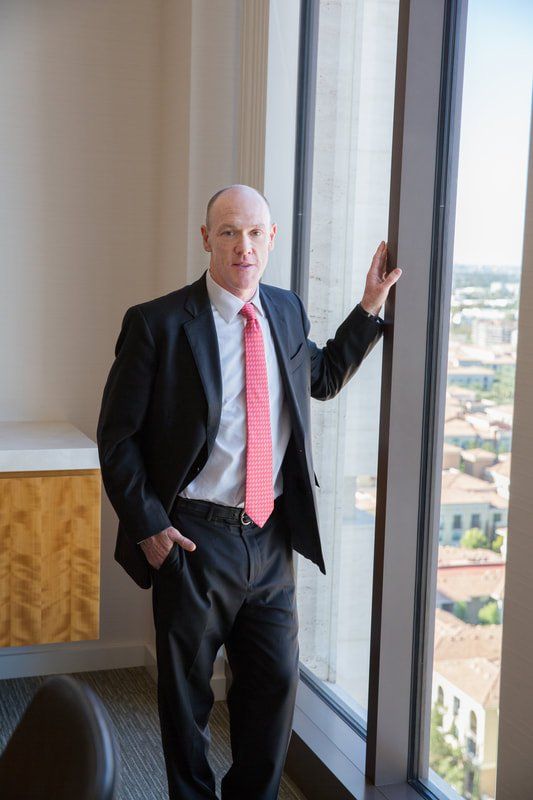 A man in a suit and tie is leaning against a window.