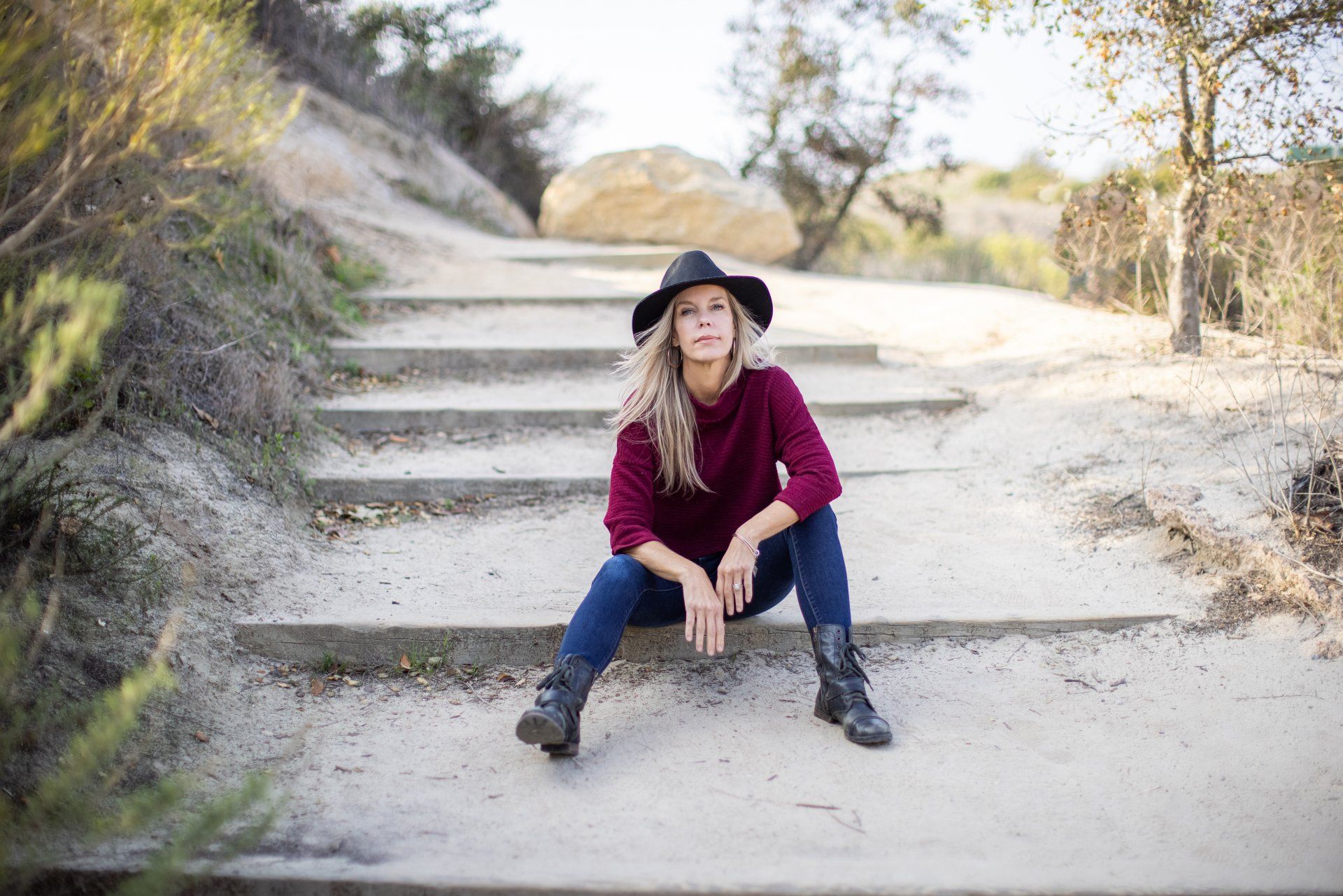 A woman in a hat is sitting on a set of stairs.