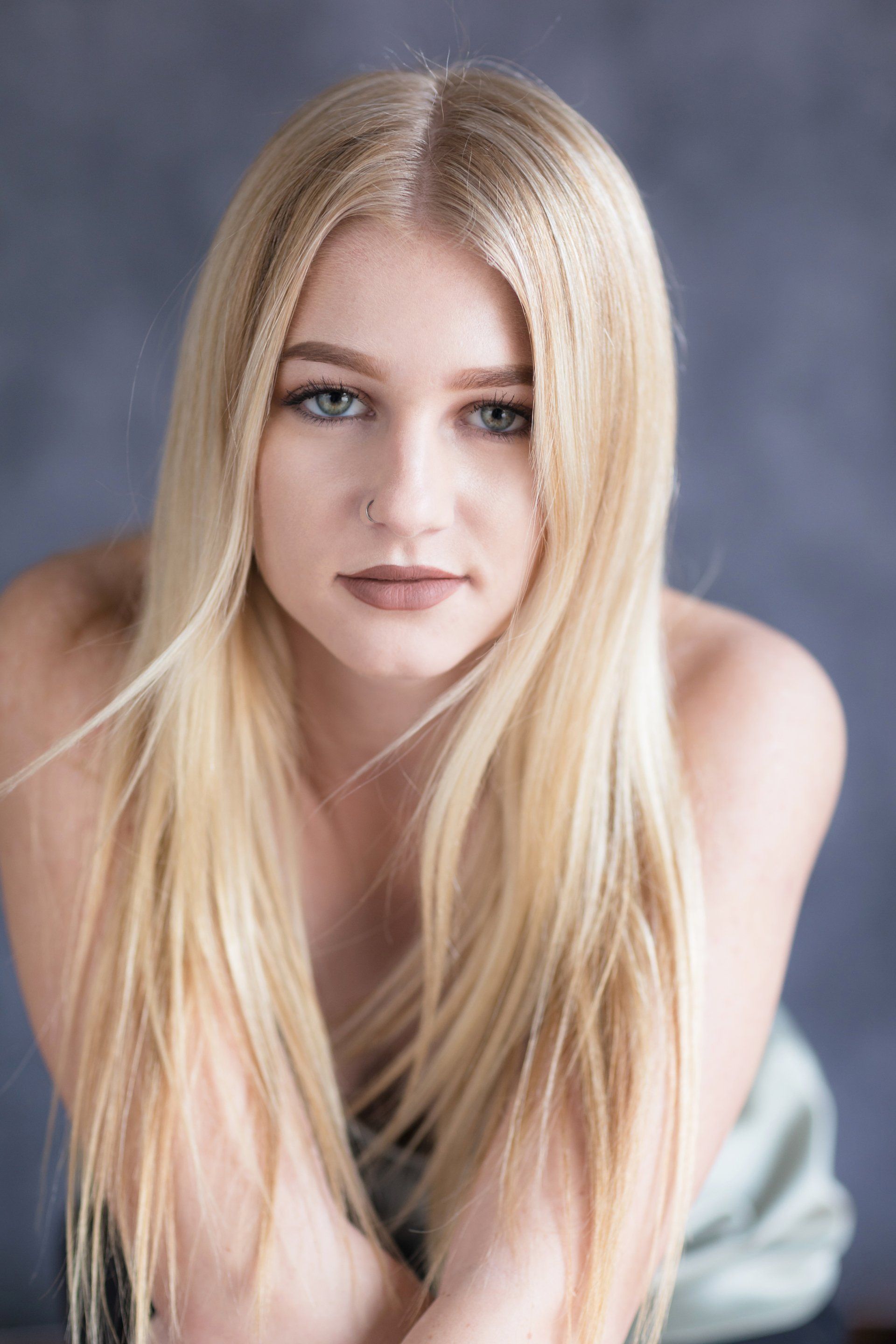Blond high school senior photographed on a grey backdrop in natural light studio in Laguna Beach.