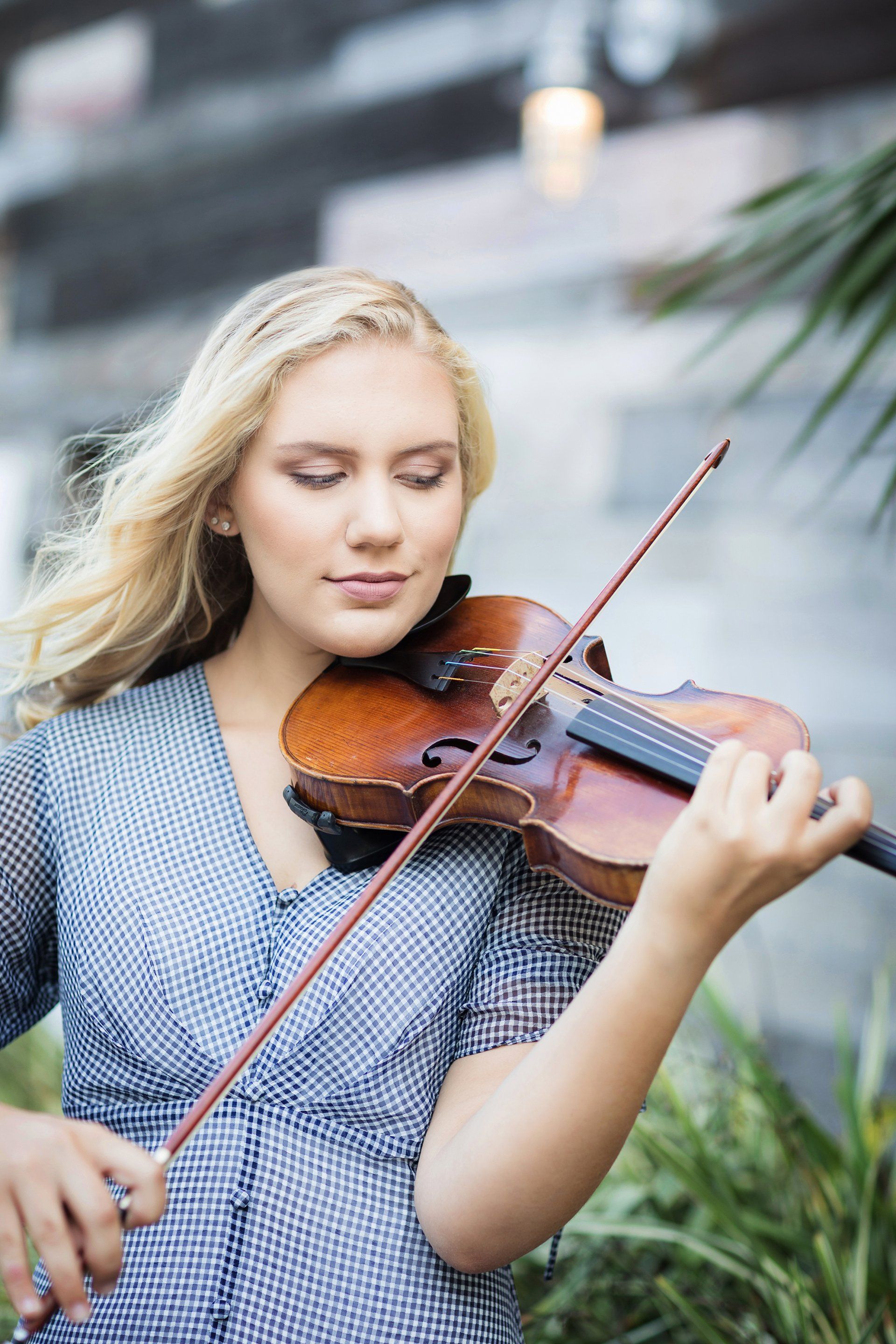A young woman is playing a violin with her eyes closed.