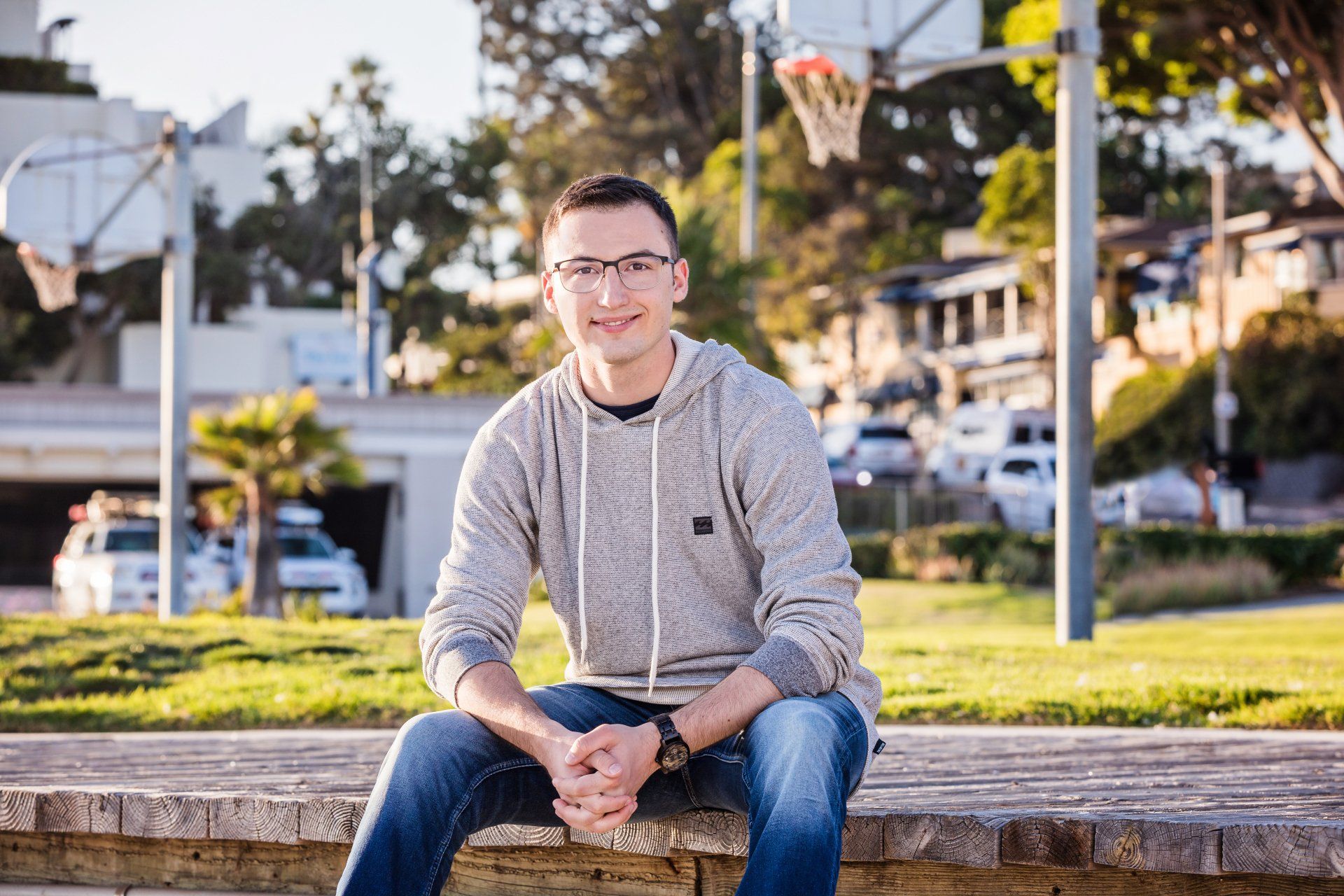 A young man is sitting on a bench in front of a basketball hoop.