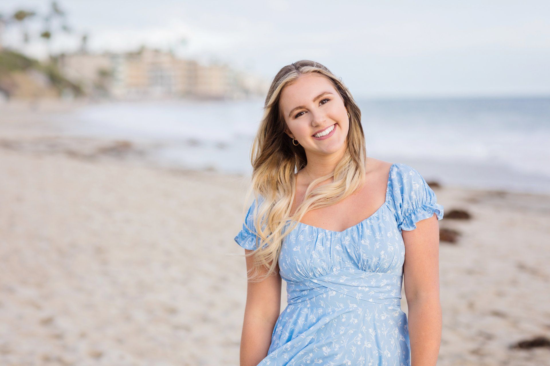A woman in a blue dress is standing on a beach.