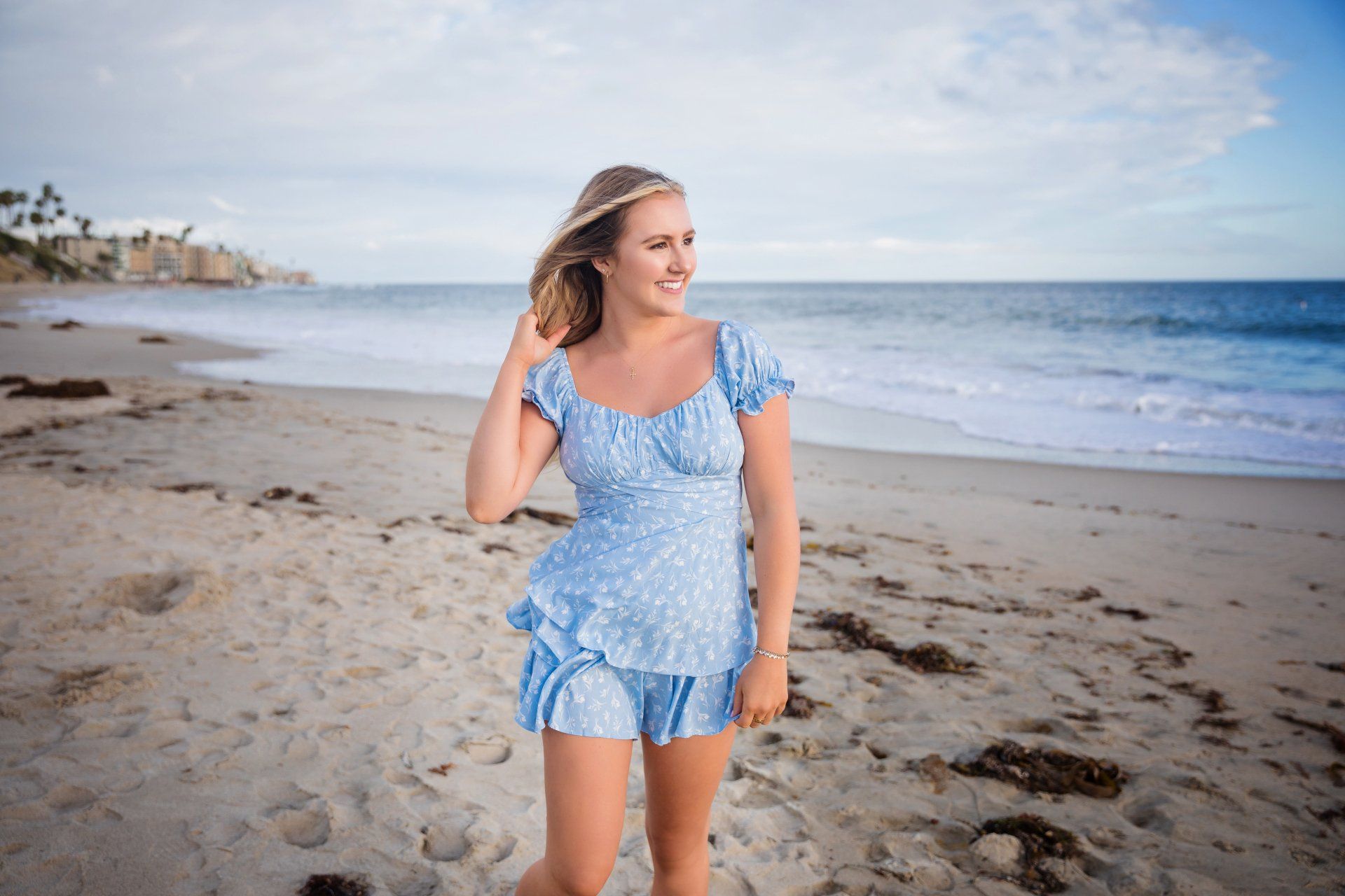A woman in a blue dress is walking on the beach.