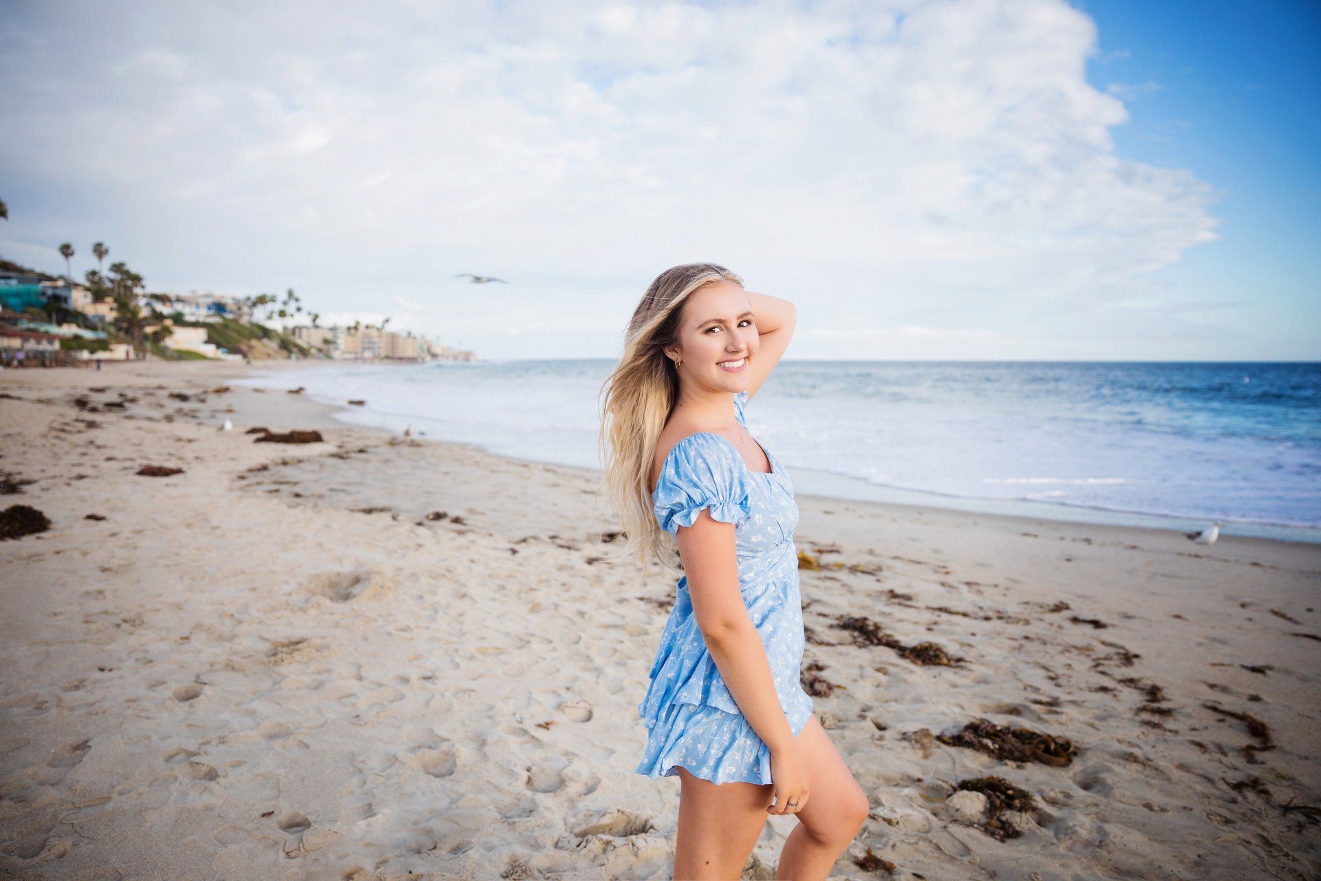 A woman in a blue dress is standing on a beach.