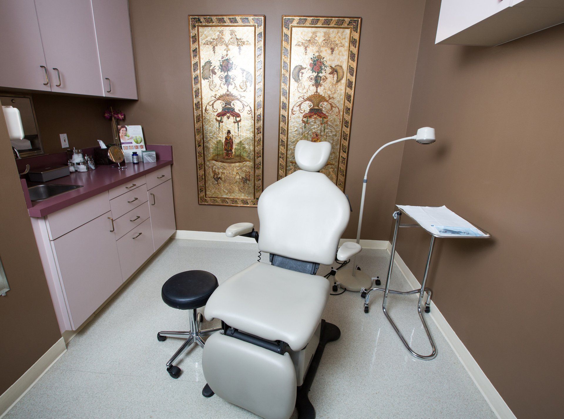 A dental office with a chair and two pictures on the wall