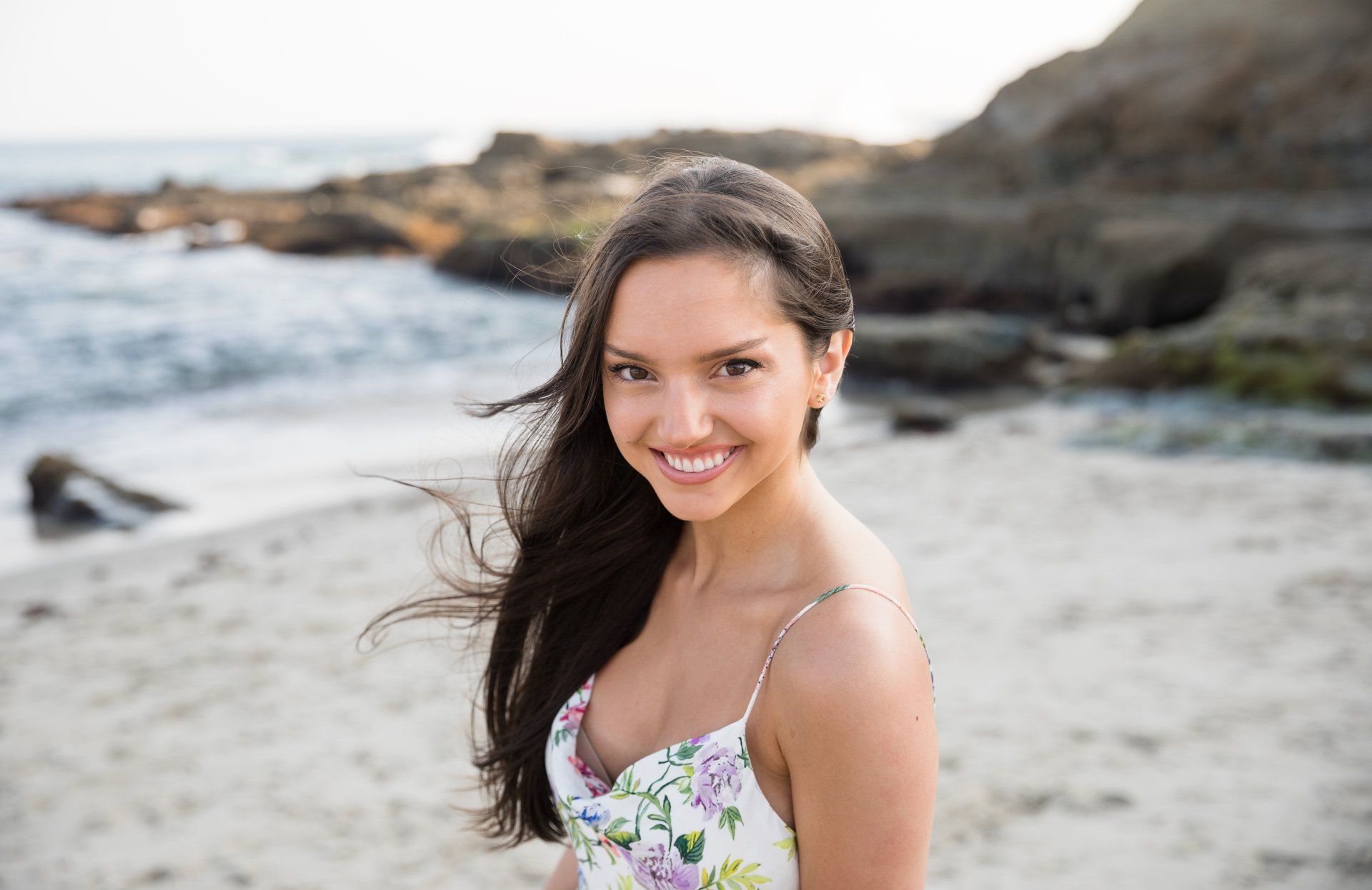 A woman is standing on a beach with her hair blowing in the wind.