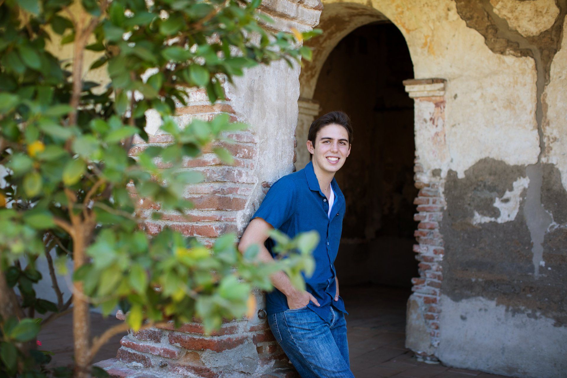 A young man is leaning against a brick wall.