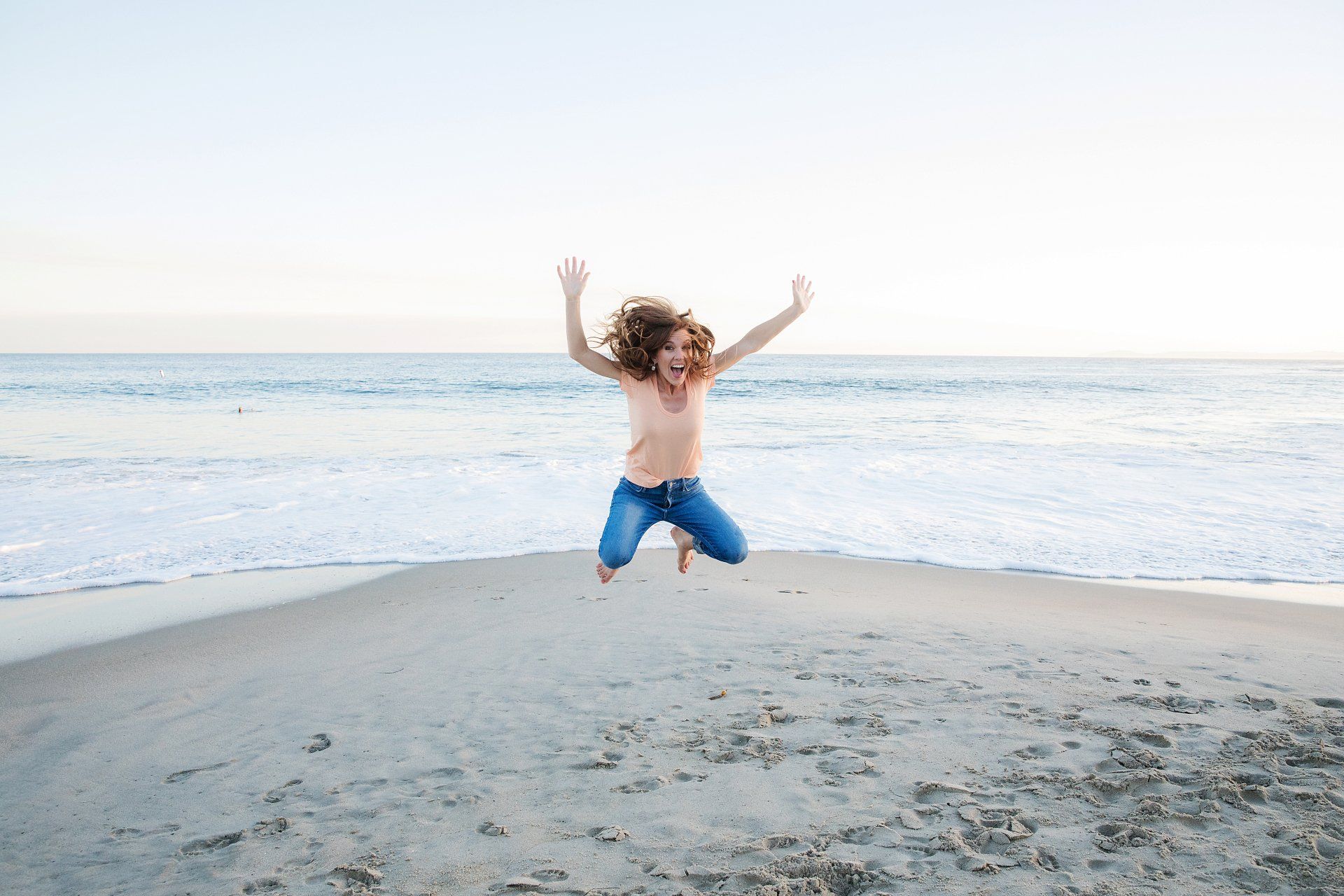 A young girl is jumping in the air on the beach.