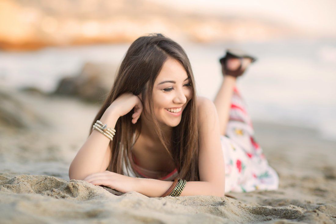 A woman is laying on her stomach on the beach.