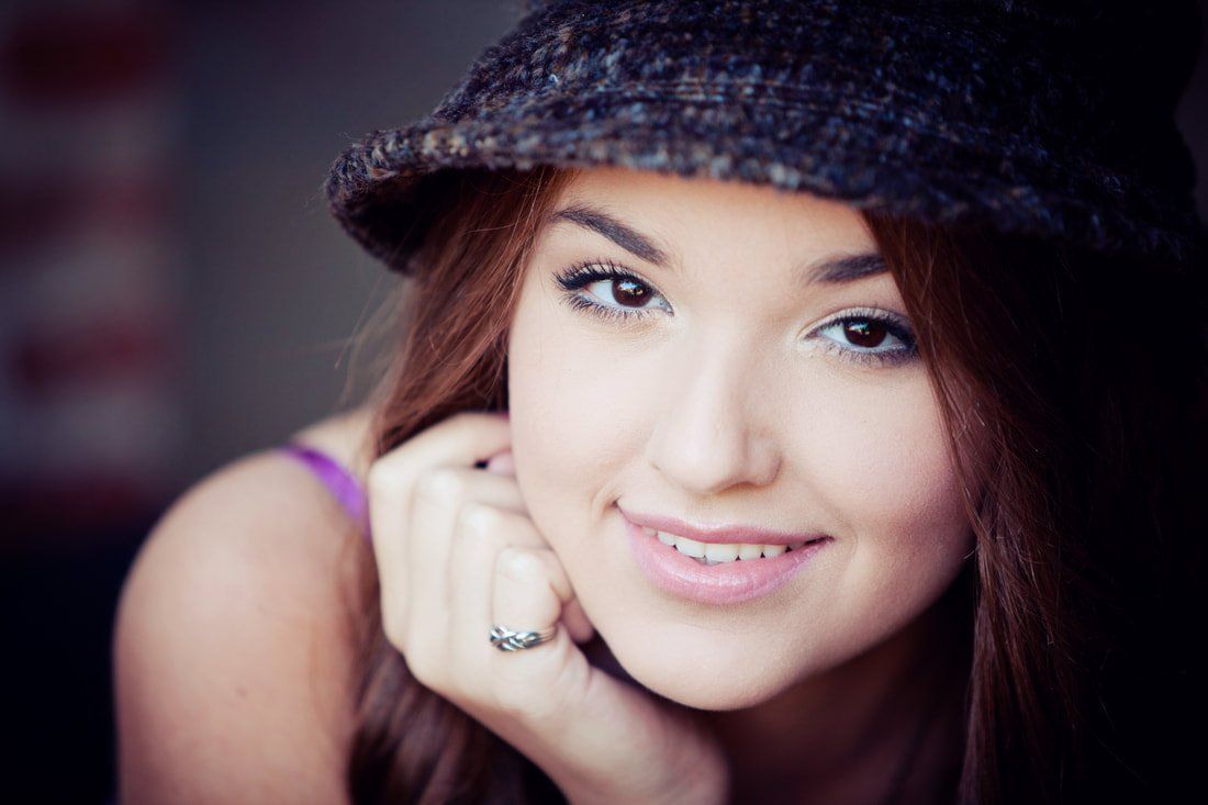 A close up of a woman wearing a hat and smiling.
