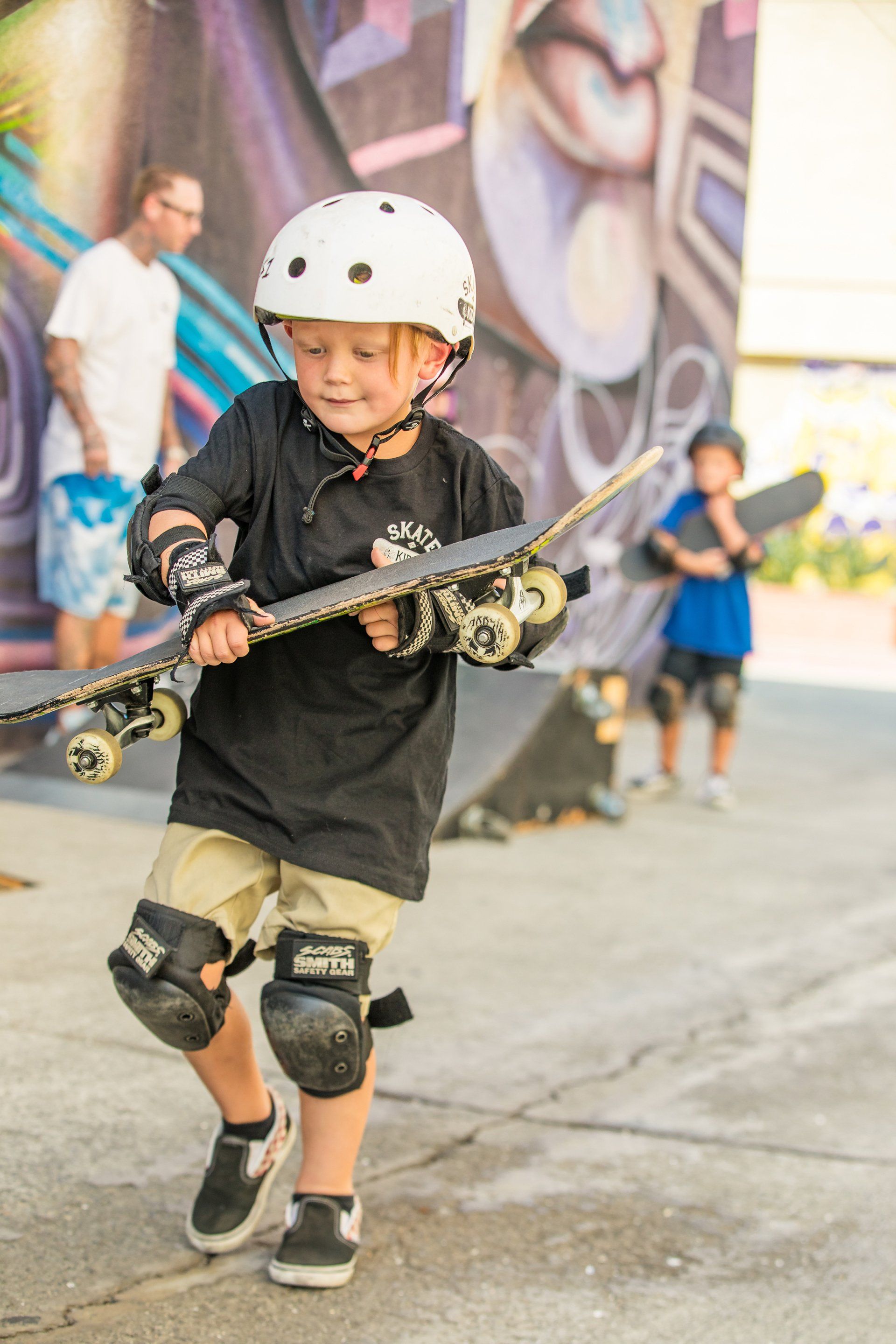 A young boy wearing a helmet is holding a skateboard.