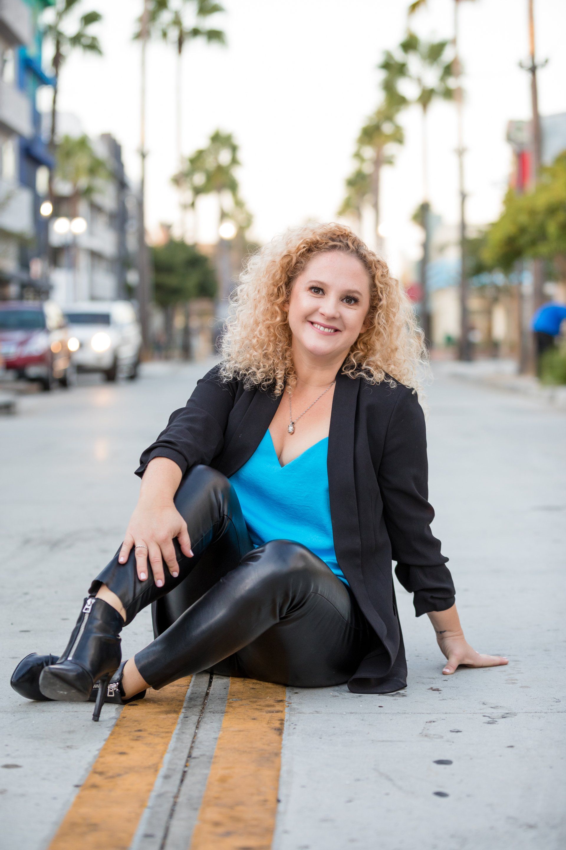 A woman is sitting on the side of the road.