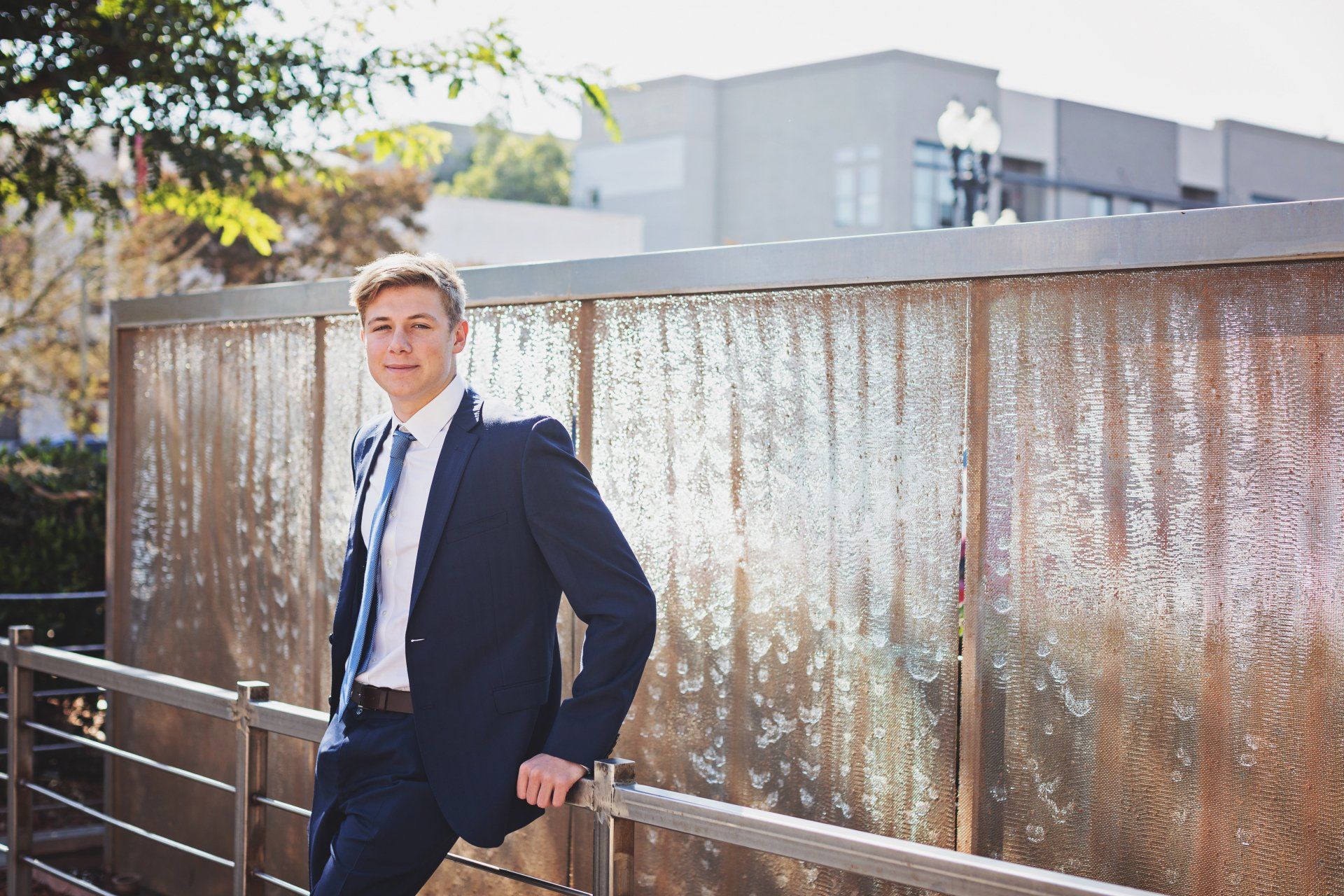 A man in a suit and tie is leaning on a railing.