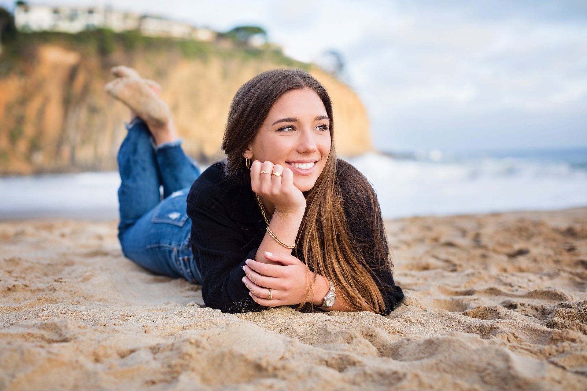 A woman is laying on her stomach on the beach.