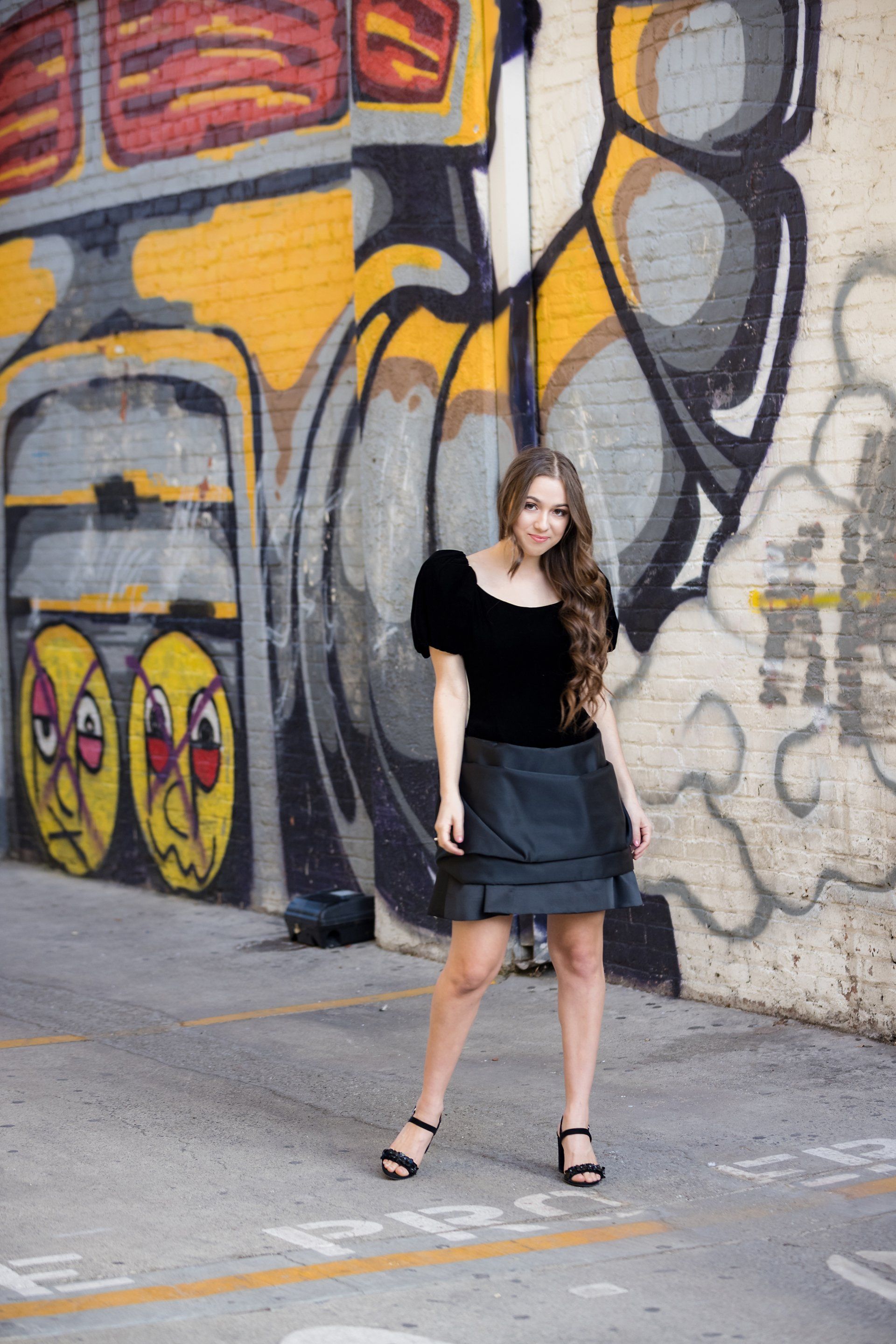A woman is standing in front of a graffiti wall.