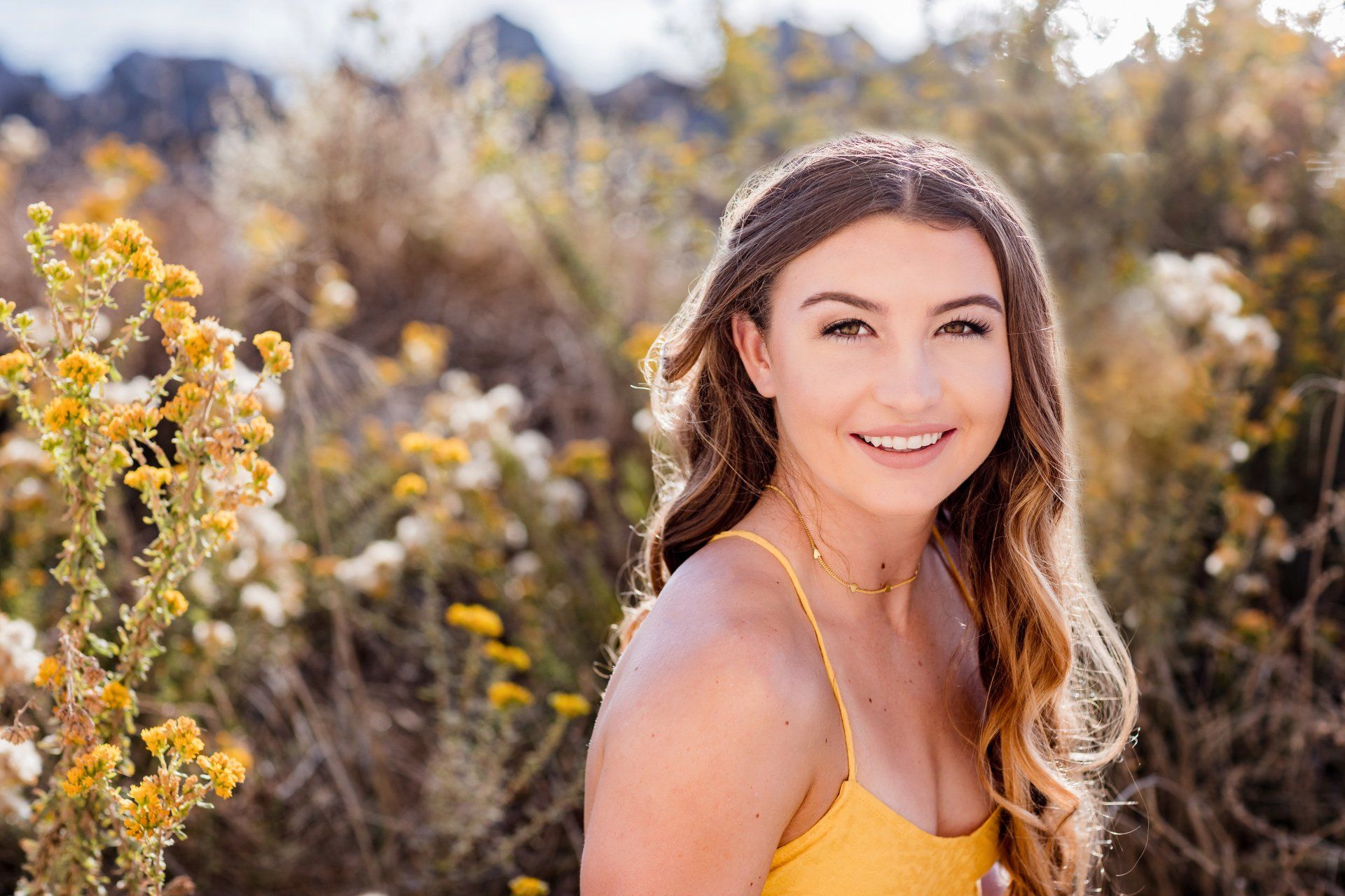 A woman in a yellow dress is standing in a field of yellow flowers.