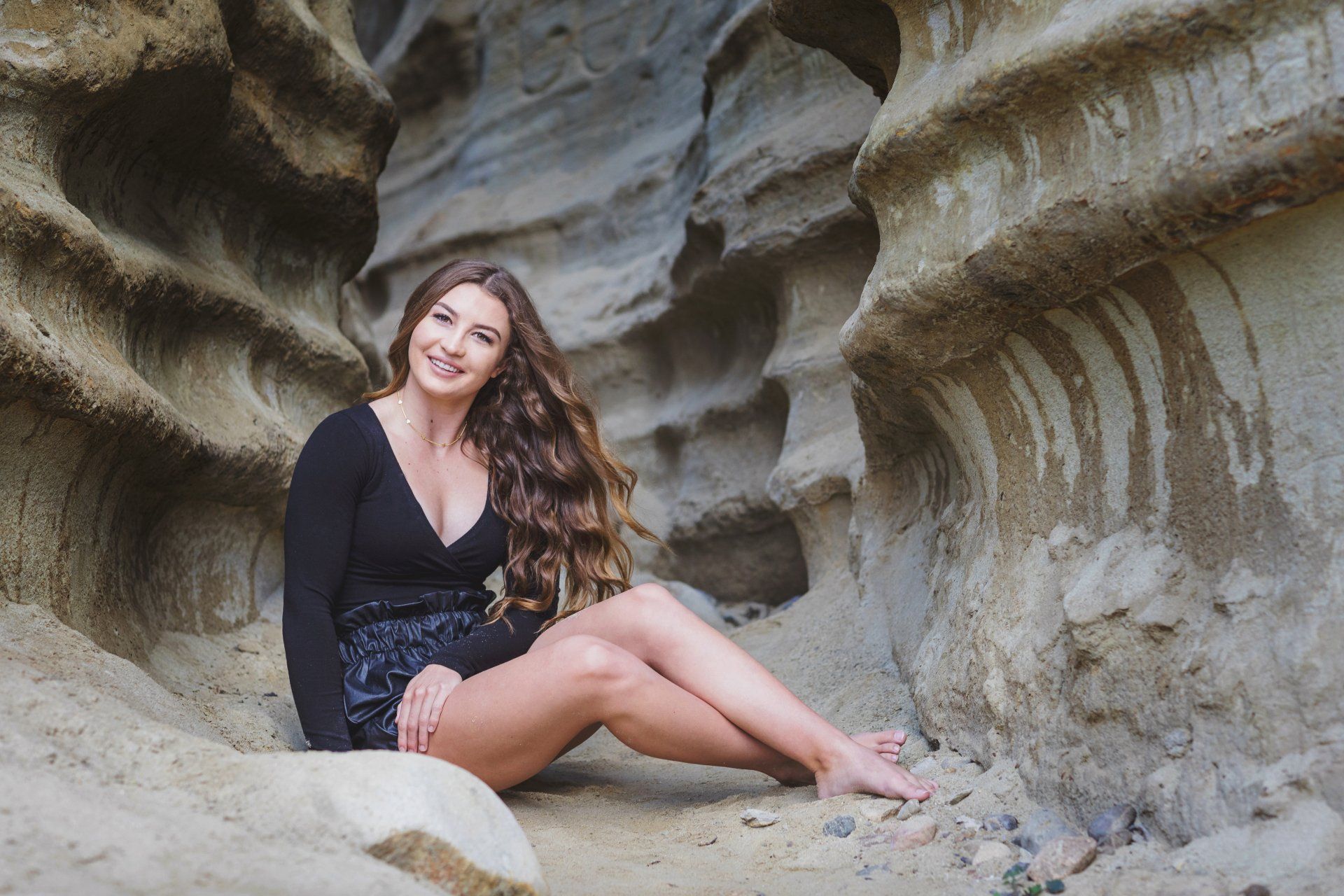 A woman is sitting on a rock in a cave.