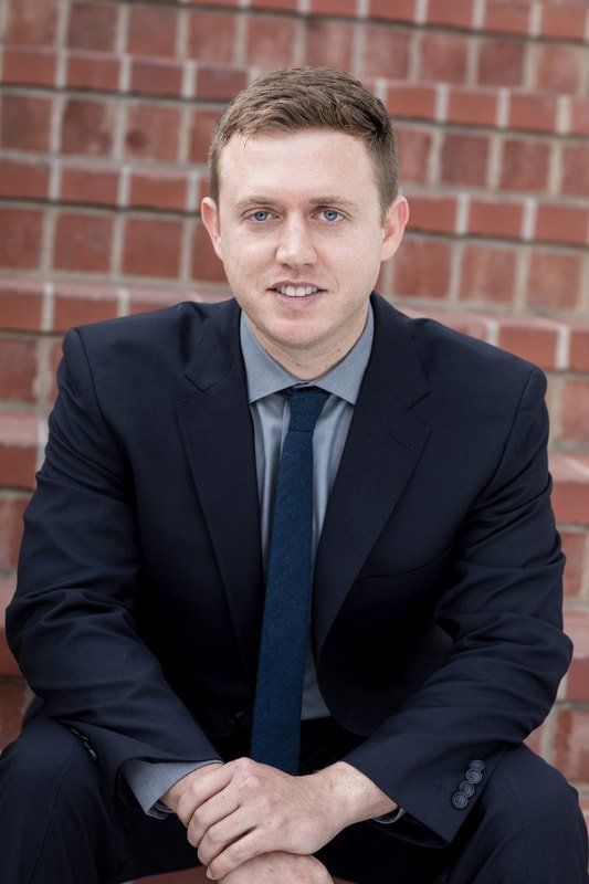 A man in a suit and tie is sitting in front of a brick wall.