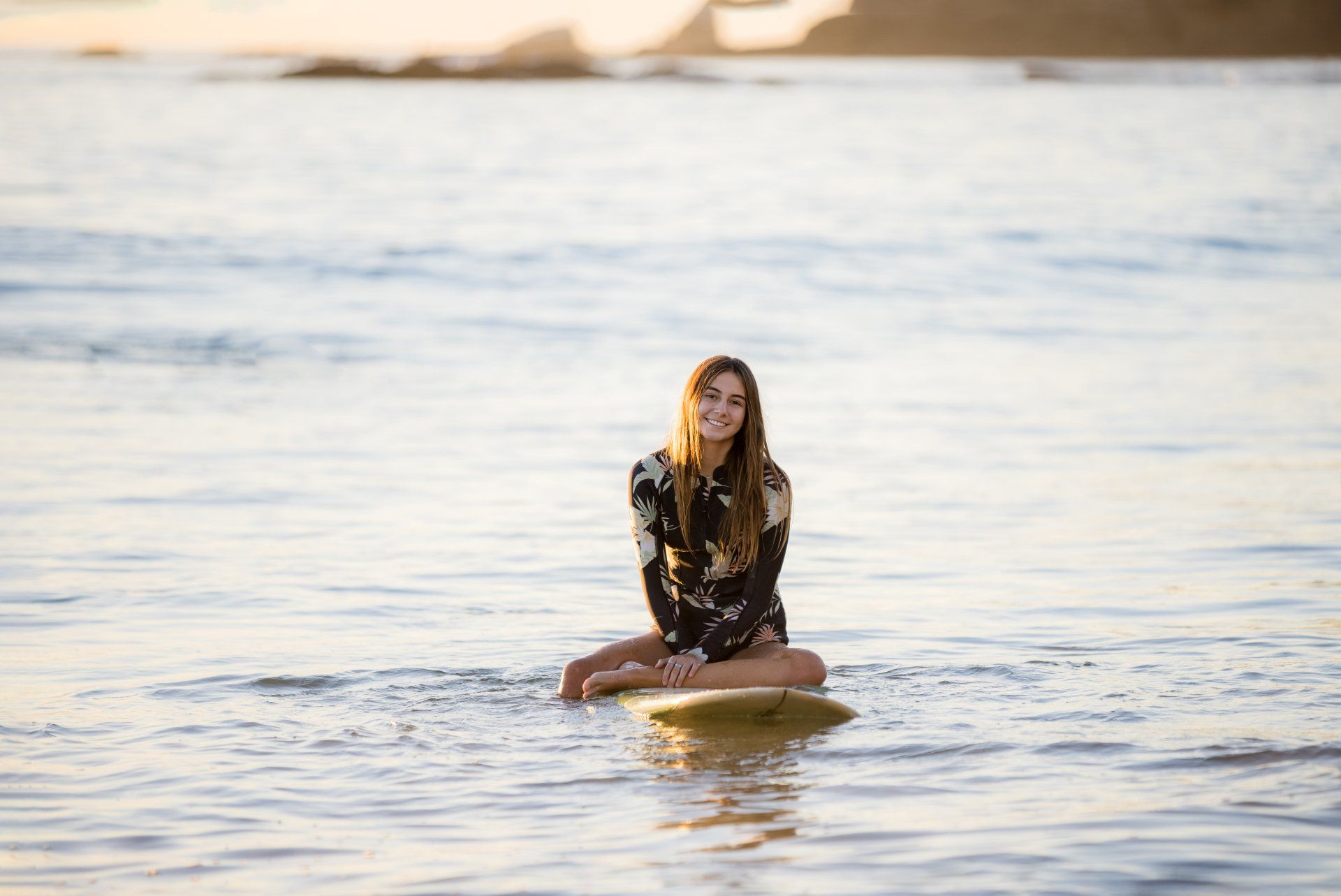 A woman is sitting on a surfboard in the ocean.