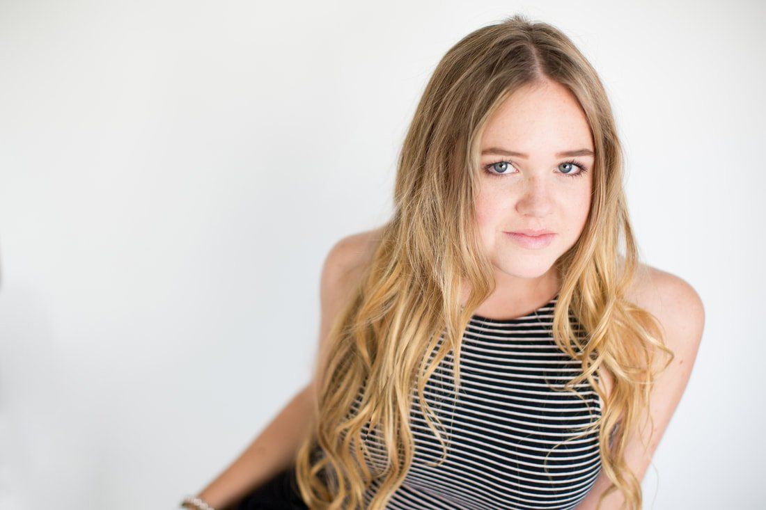 A young woman with long blonde hair is wearing a black and white striped top.