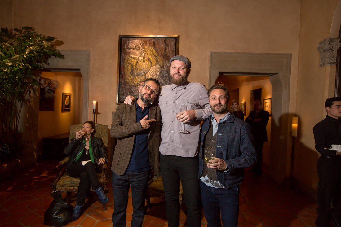 Three men are standing next to each other in a room holding wine glasses.