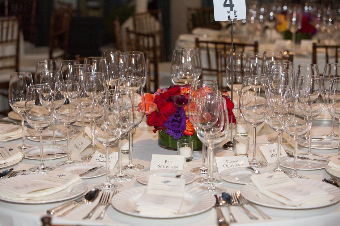 A table set for a dinner party with wine glasses and plates.