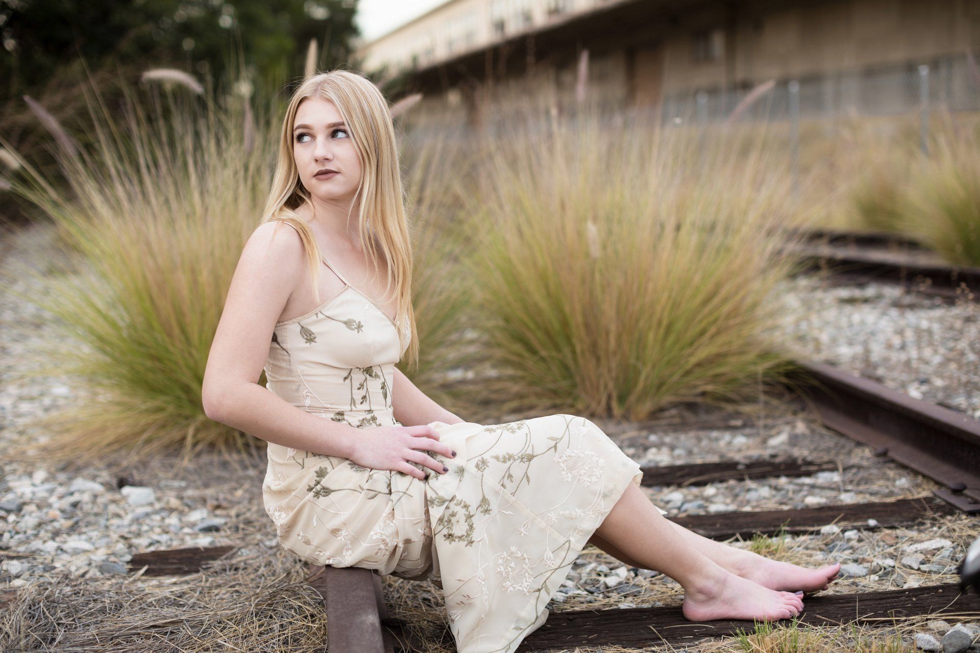 A woman in a white dress is sitting on train tracks.